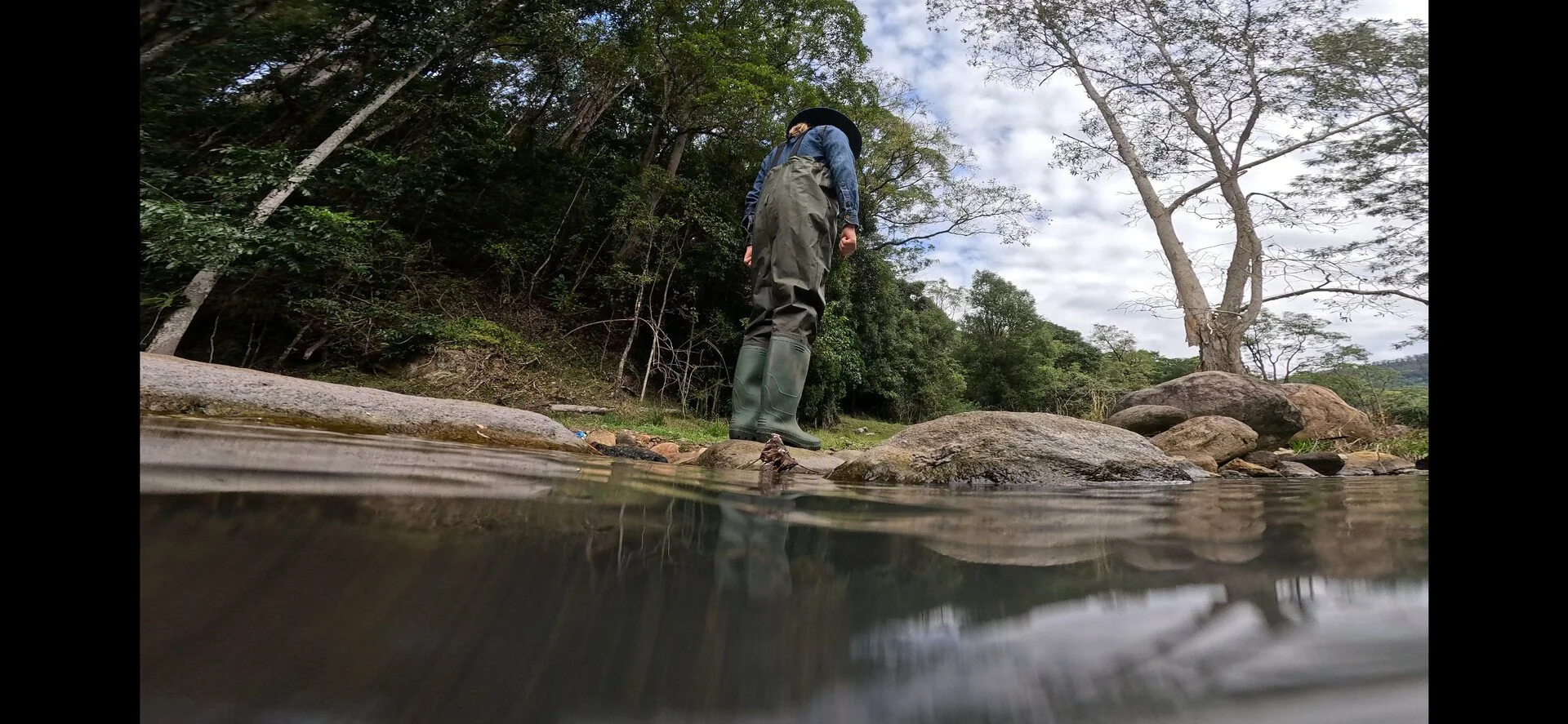 Still image from the film "My Friend Artemis" showing a person standing by a river