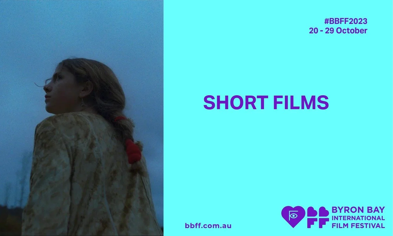 A young girl with braided hair gazes upwards against a dusky backdrop. Text on a blue panel reads "SHORT FILMS," promoting Byron Bay Film Festival 2023.