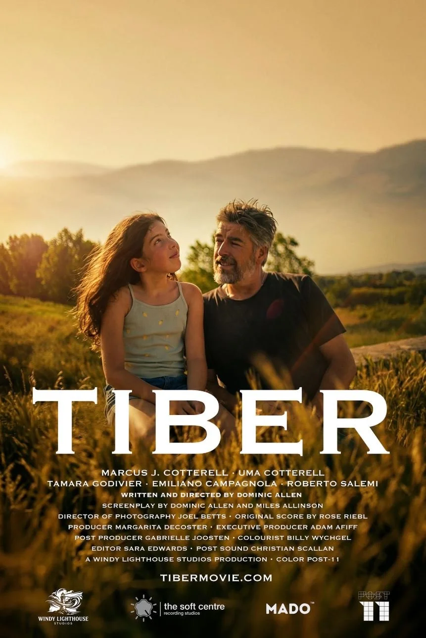 Poster for Tiber, written and directed by Dominic Allen. A man and a young girl sit close together in a golden, sunlit field, smiling at each other, with hills in the background. Title in bold white letters below.