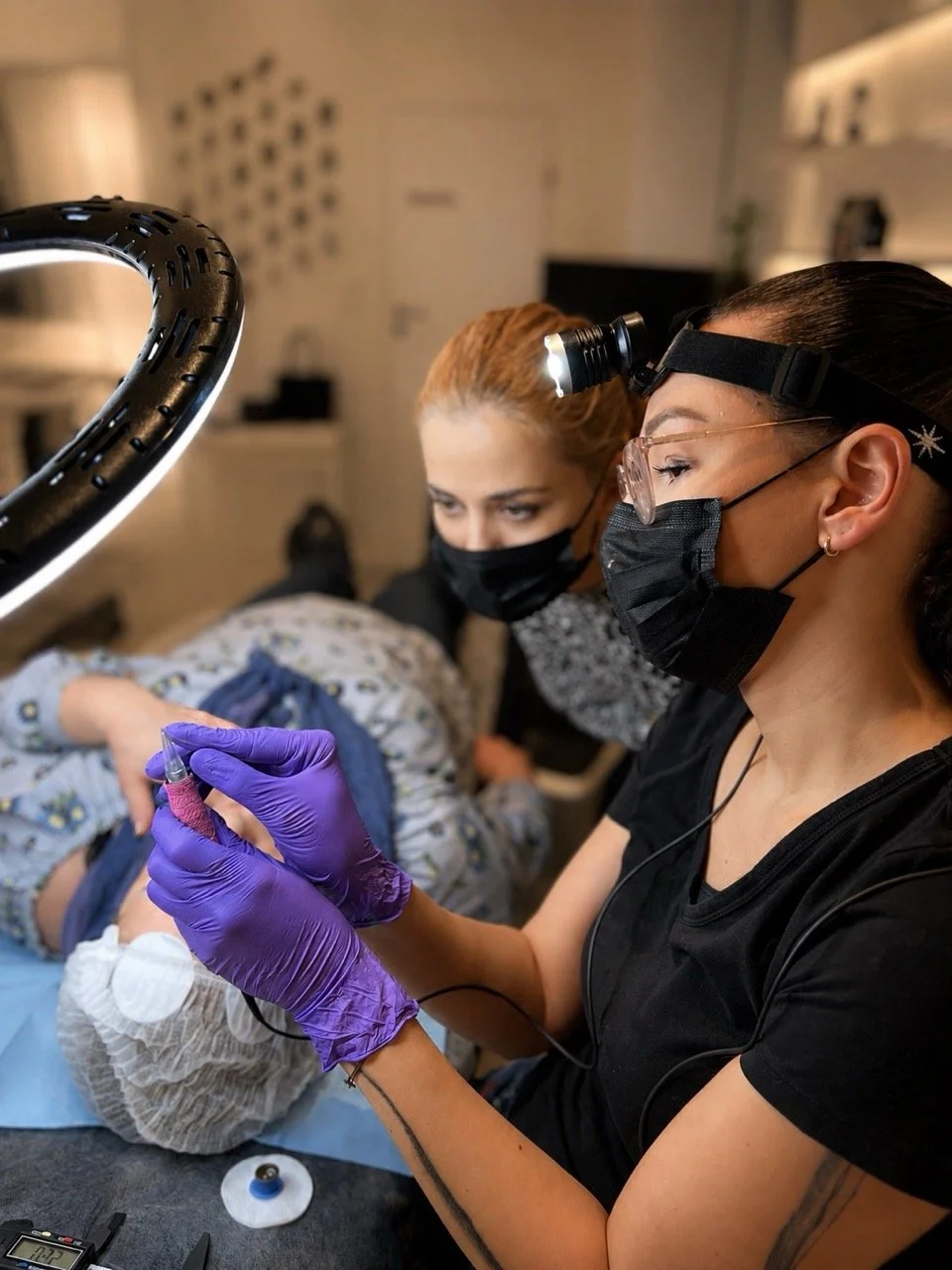 PMU-Schülerin bereitet während einer Permanent-Make-up-Schulung in Wien das Pigmentiergerät für die Behandlung vor.