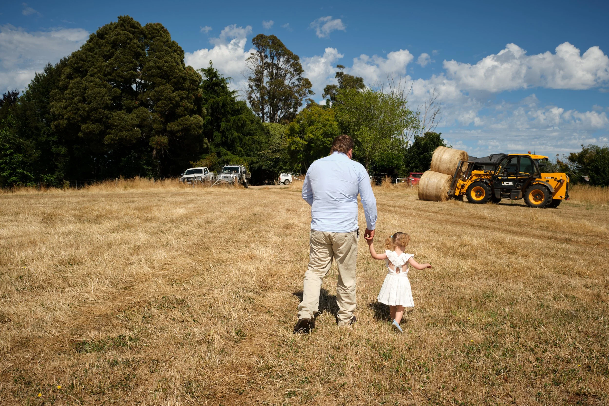 clark-launceston-extended-family-father-daughter-walking-farm-field-hay-bales.jpeg