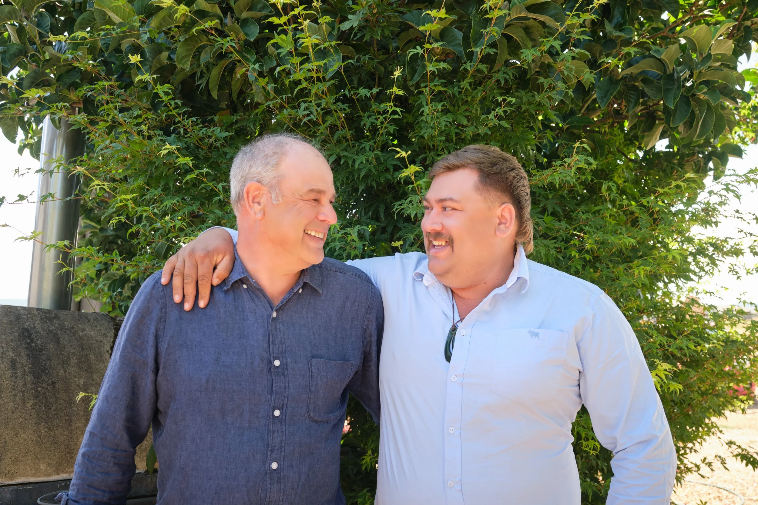 clark-launceston-extended-family-two-men-smiling-outdoors-hugging-under-green-tree.jpeg