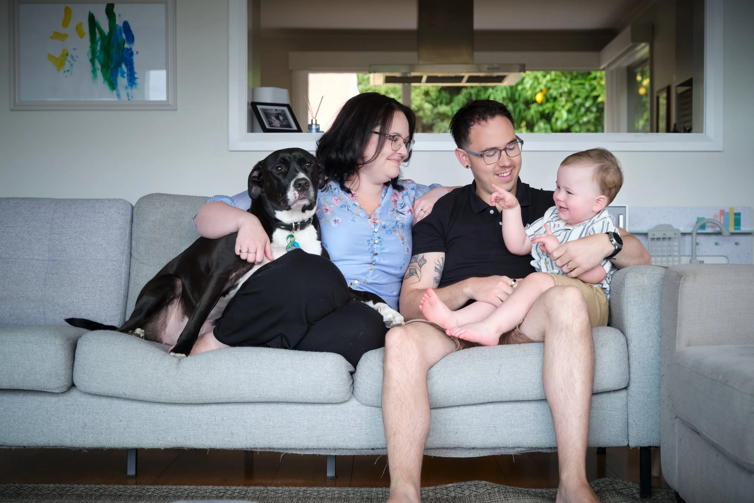 petty-riverside-family-portrait-happy-family-with-dog-and-toddler-on-couch.jpeg