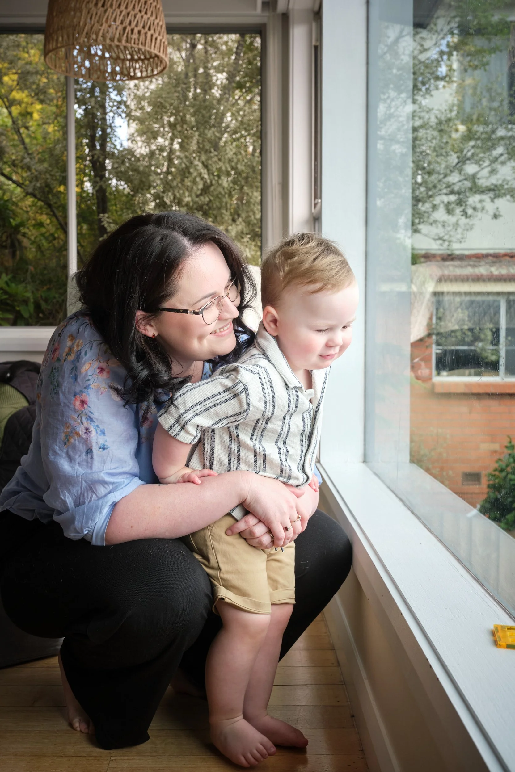 petty-riverside-family-portrait-mum-hugging-toddler-looking-out-window.jpeg