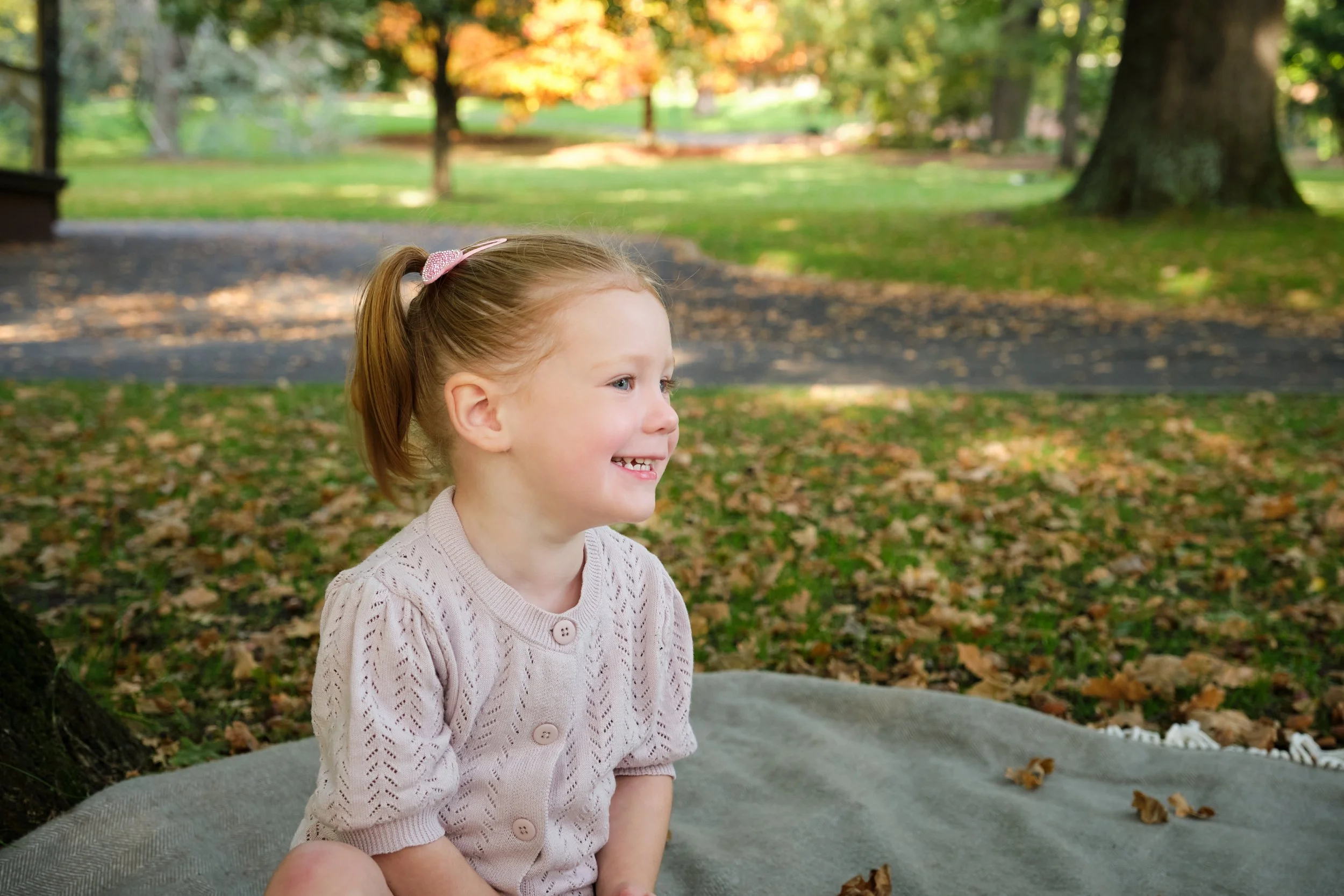 henderson-city-park-launceston-family-portrait-photography-smiling-toddler-on-blanket-autumn-leaves.jpeg