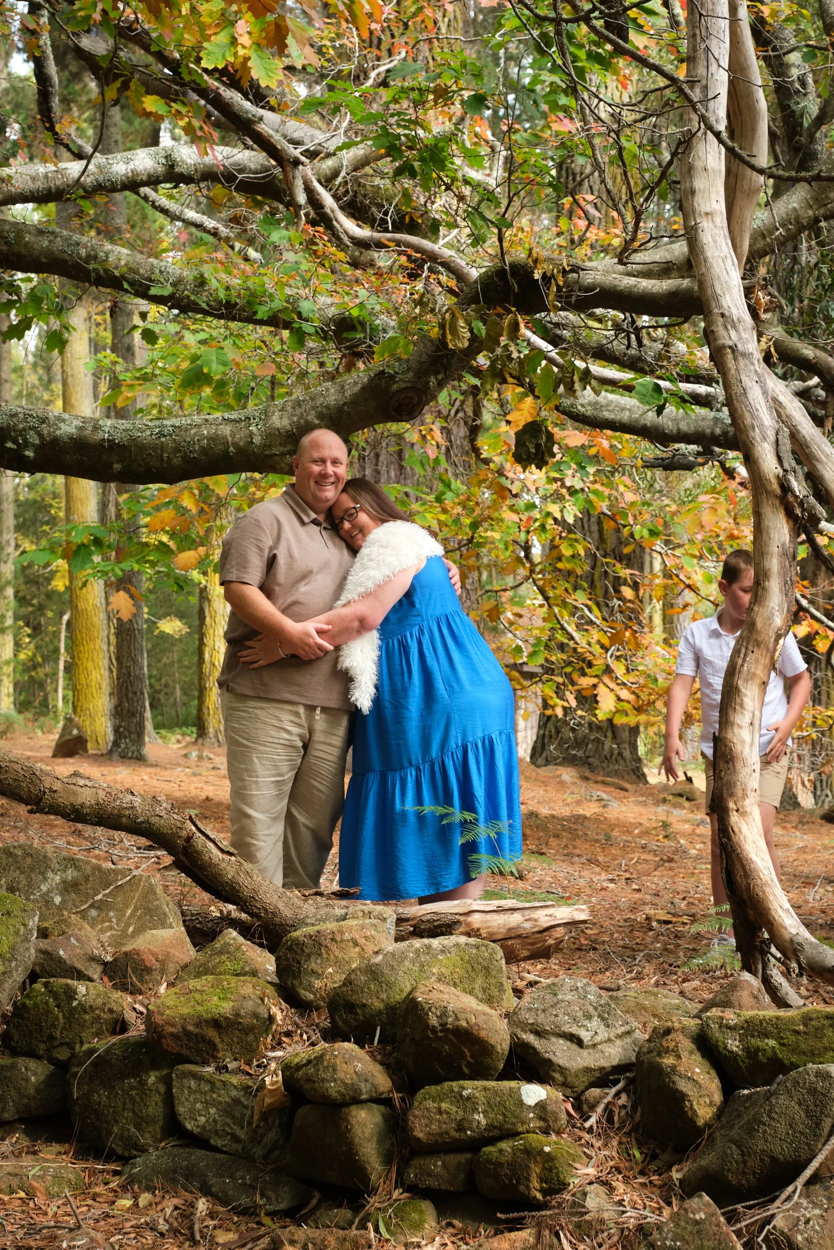 north-hollybank-launceston-family-photography-couple-hugging-forest-autumn-child-exploring.jpeg