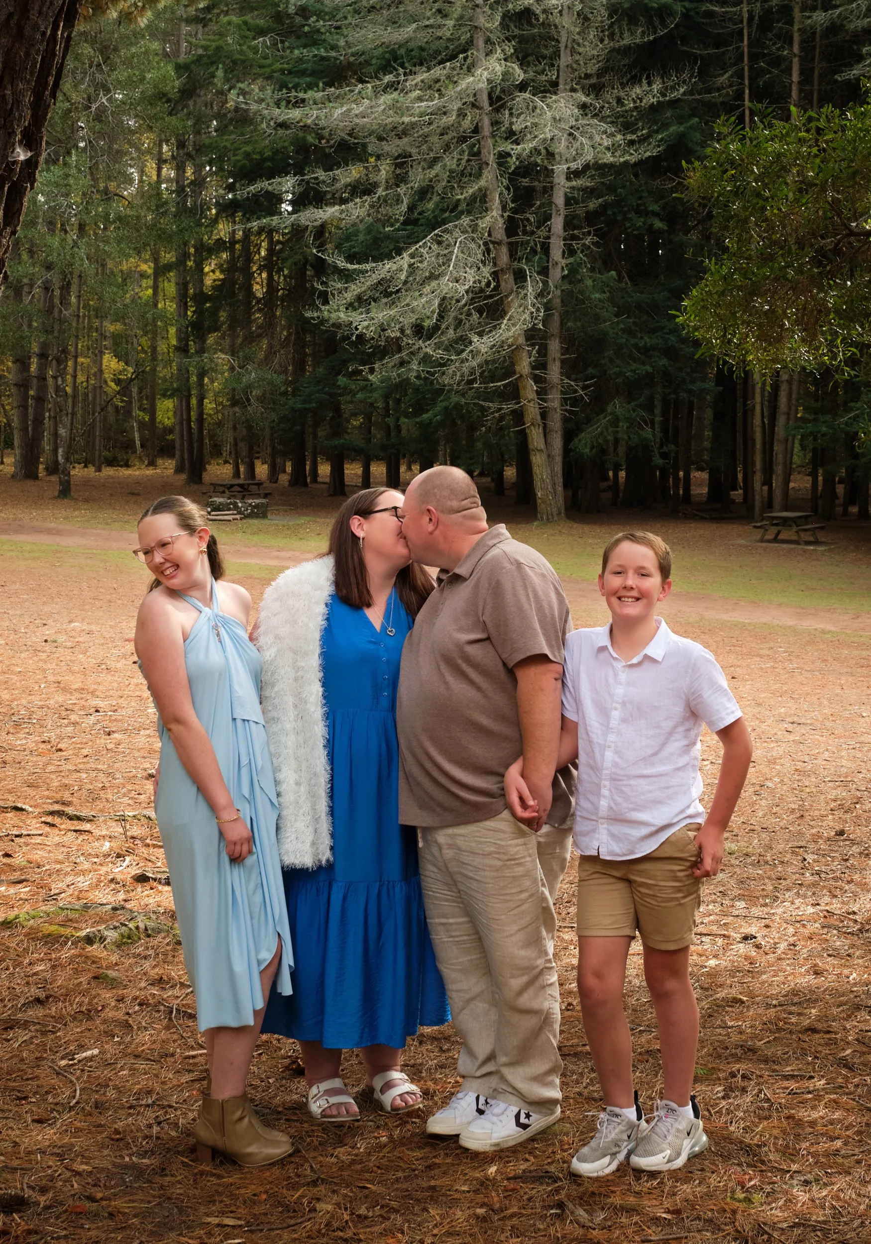 north-hollybank-launceston-family-photography-parents-kissing-with-children-smiling-in-forest.jpeg