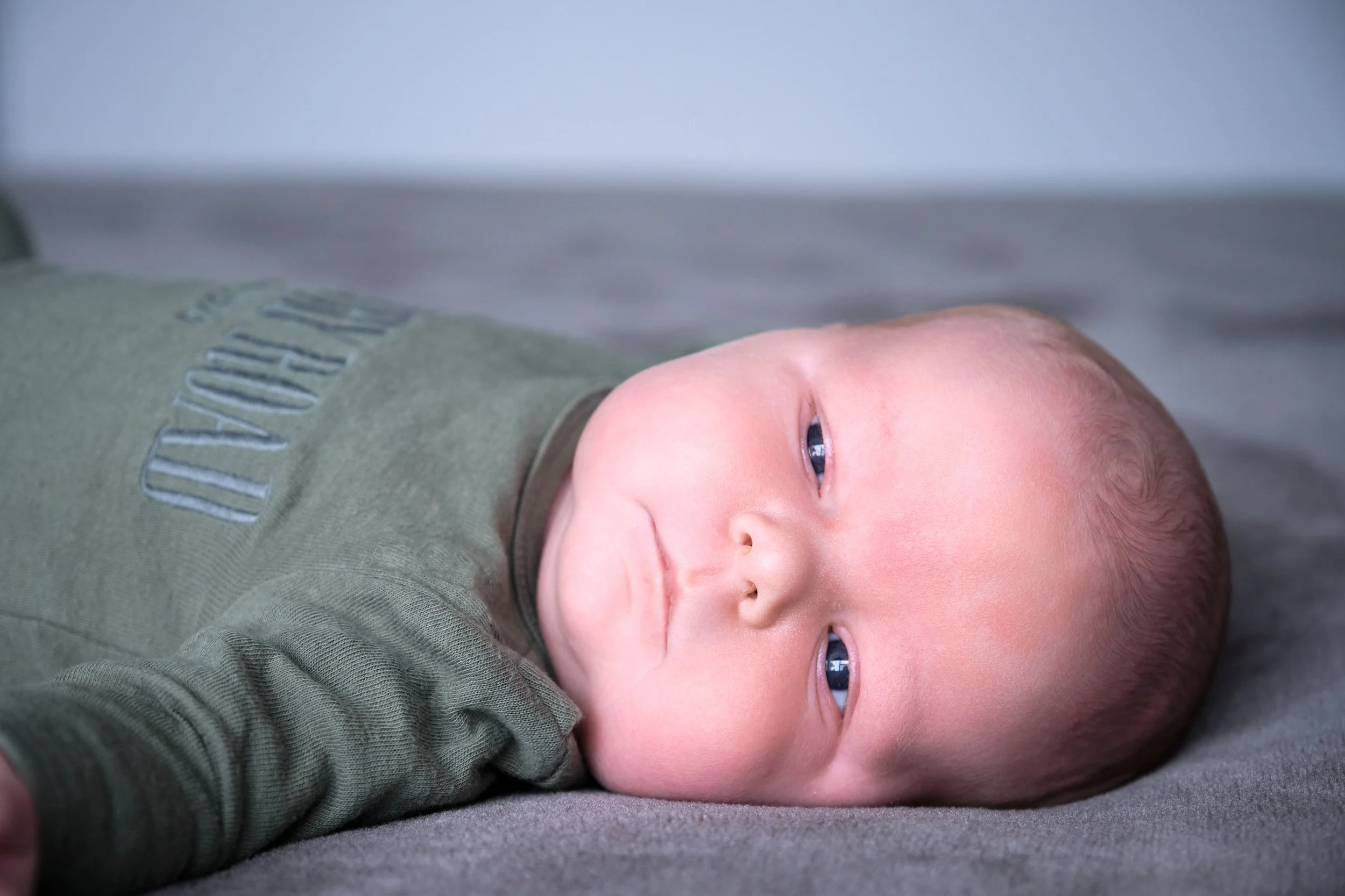 lawrence-launceston-newborn-family-photography-baby-lying-on-bed-looking-calm.jpeg