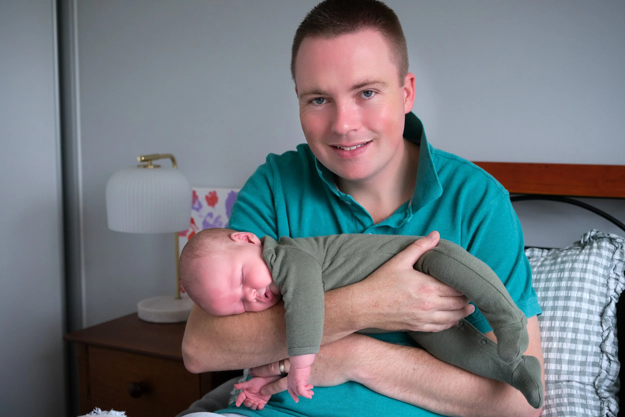 lawrence-launceston-newborn-family-photography-dad-holding-sleeping-baby-on-bed.jpeg