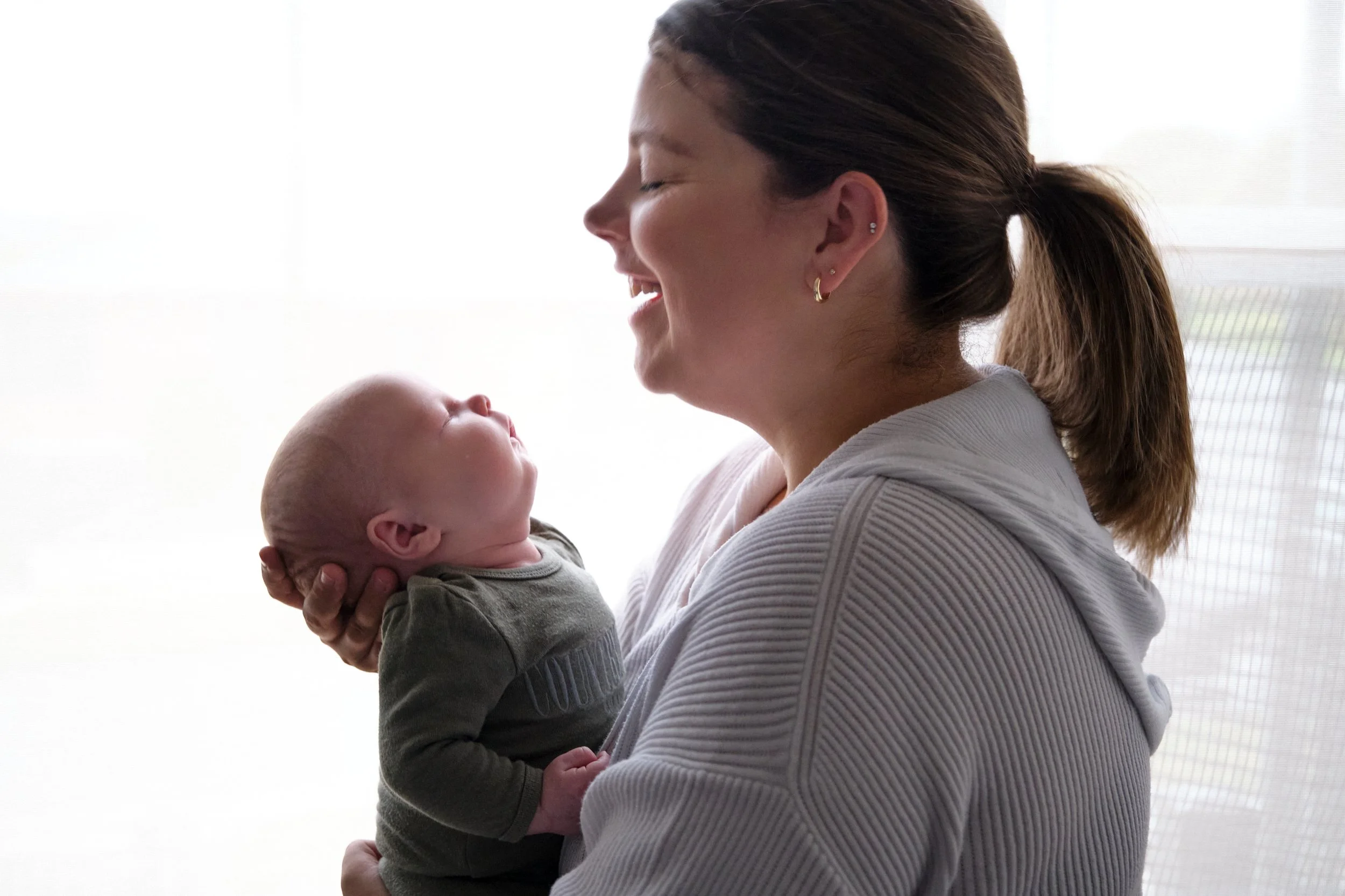 lawrence-launceston-newborn-family-photography-mother-smiling-holding-sleeping-baby.jpeg