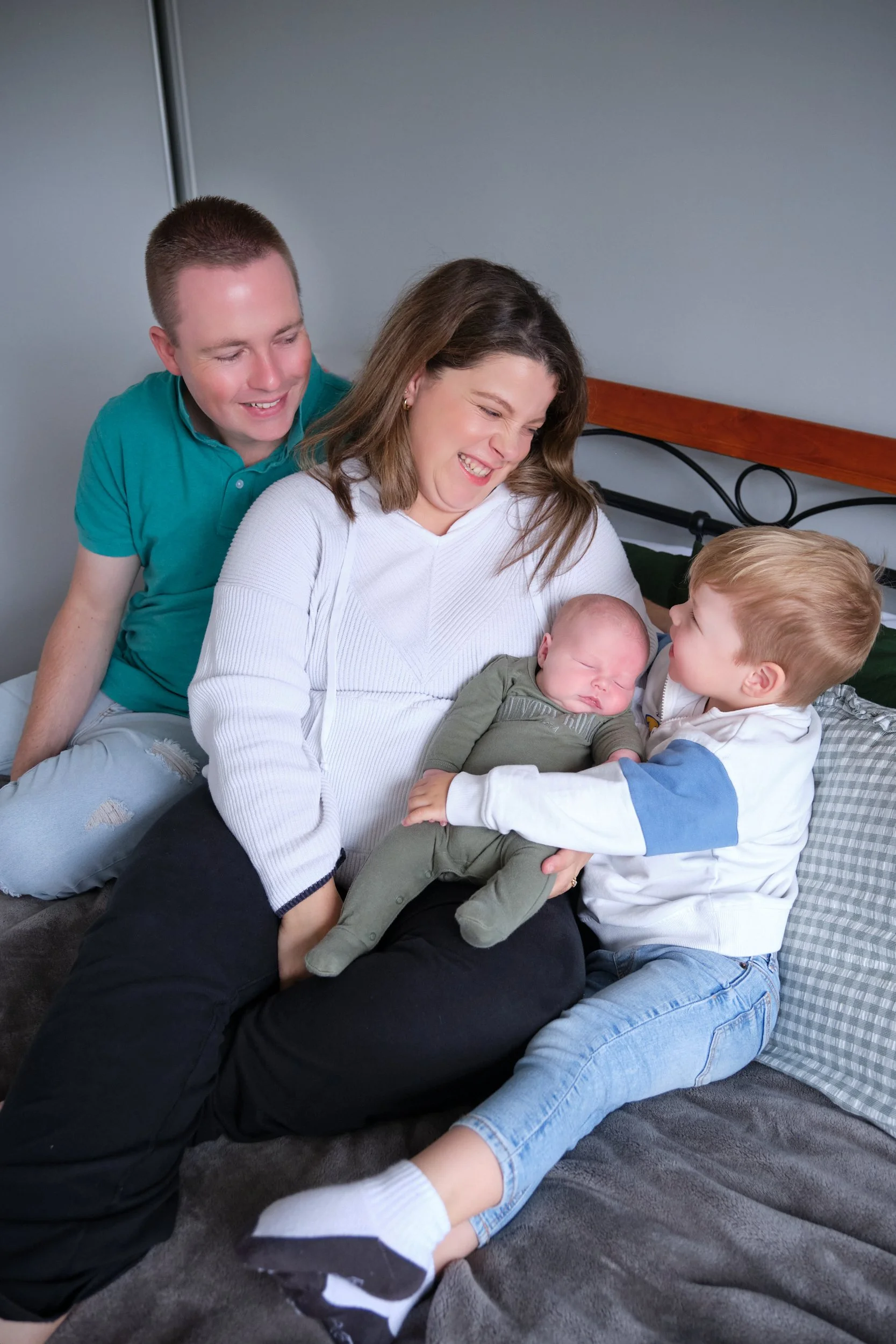 lawrence-launceston-newborn-family-photography-parents-cuddling-toddler-holding-baby-on-bed.jpeg