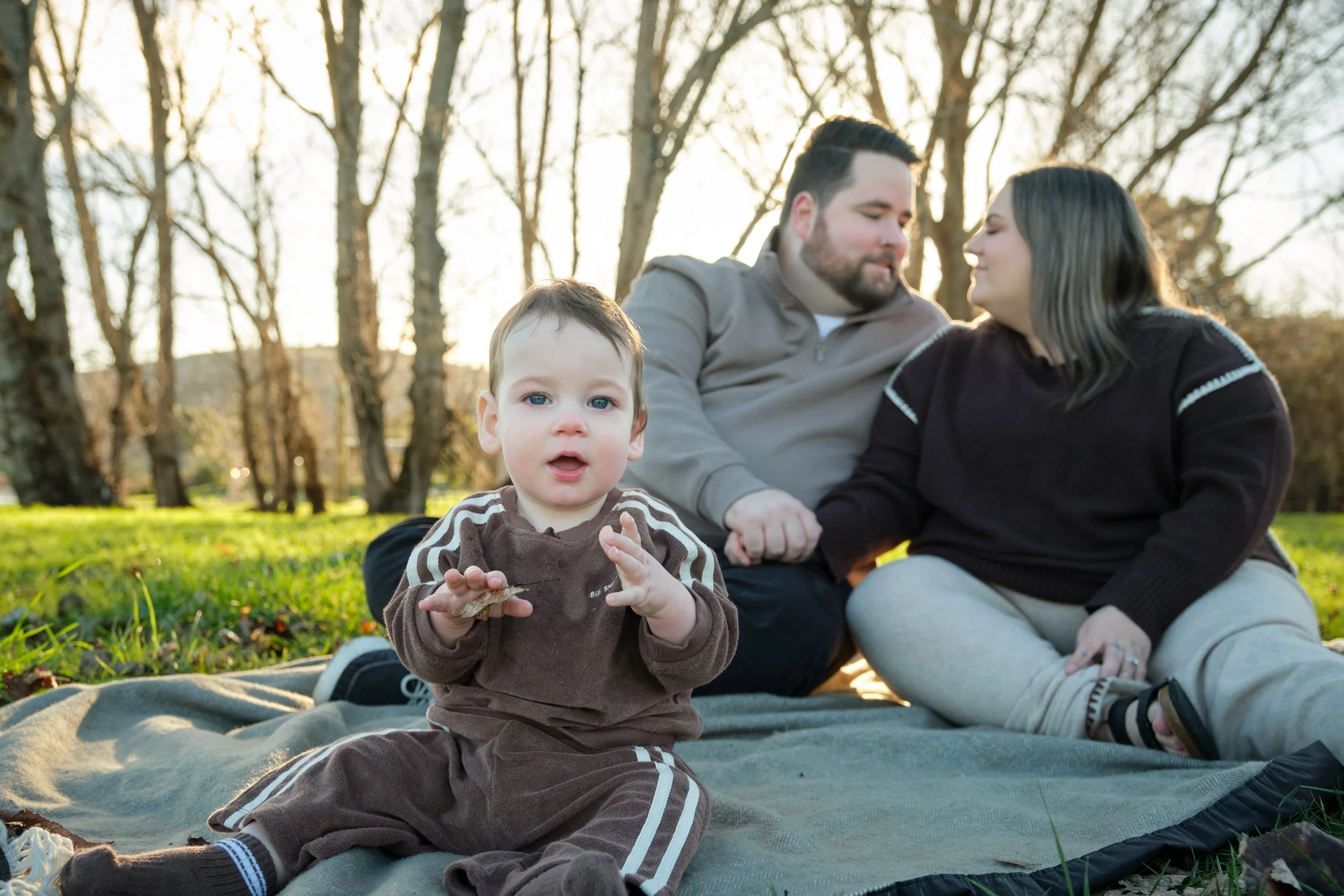 williams-hadspen-river-launceston-family-portrait-baby-sitting-parents-holding-hands.jpeg