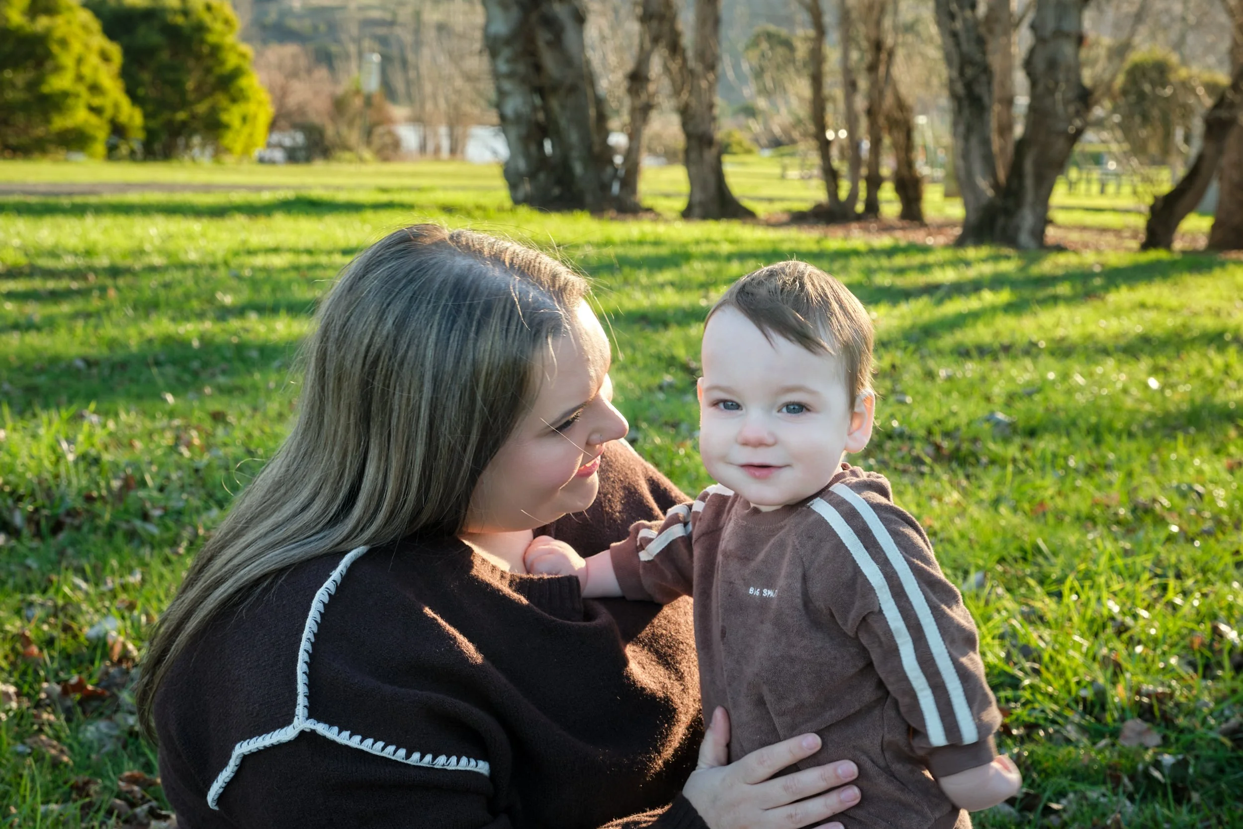williams-hadspen-river-launceston-family-portrait-mother-holding-smiling-baby-on-grass.jpeg