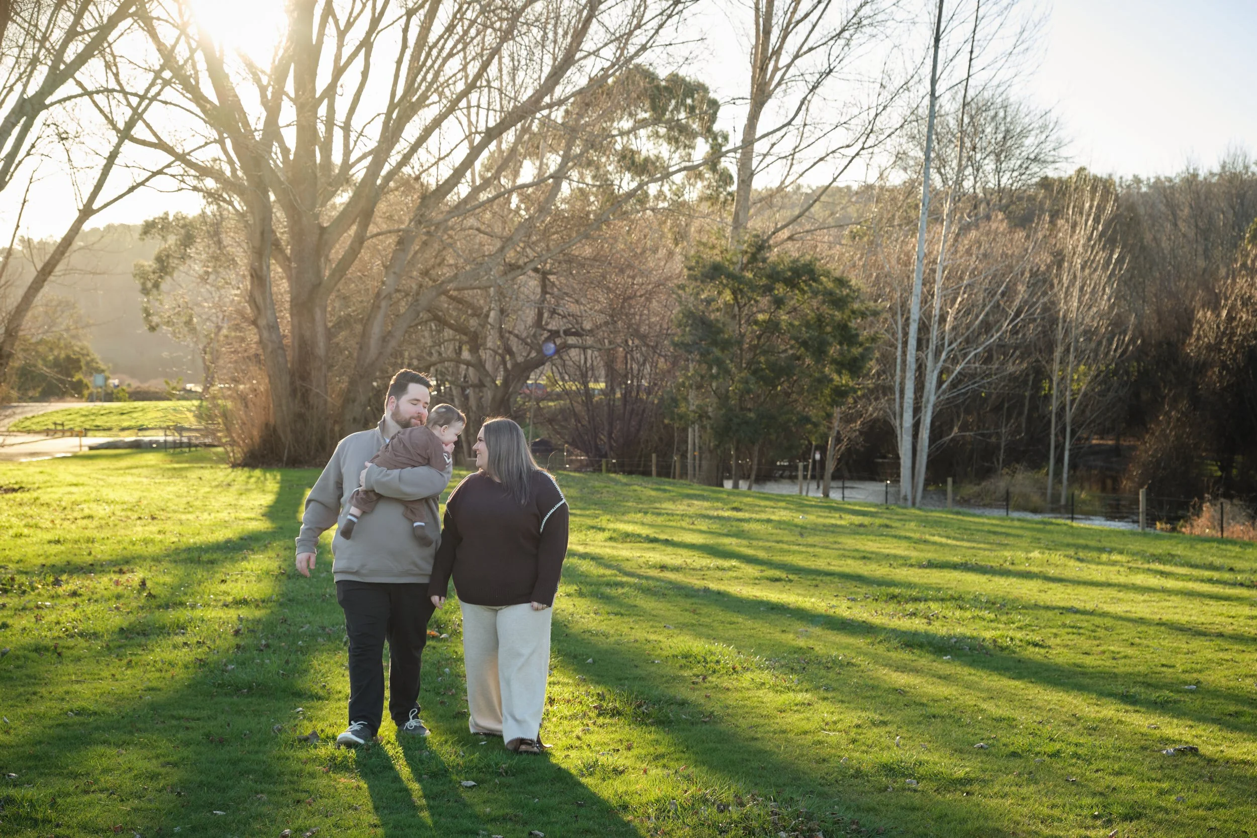 williams-hadspen-river-launceston-family-portrait-parents-walking-holding-baby-sunset.jpeg