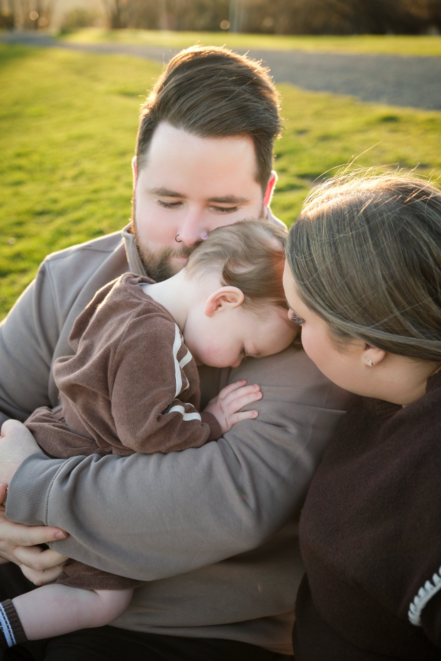 williams-hadspen-river-launceston-family-portrait-session-parents-cuddling-sleepy-toddler.jpeg