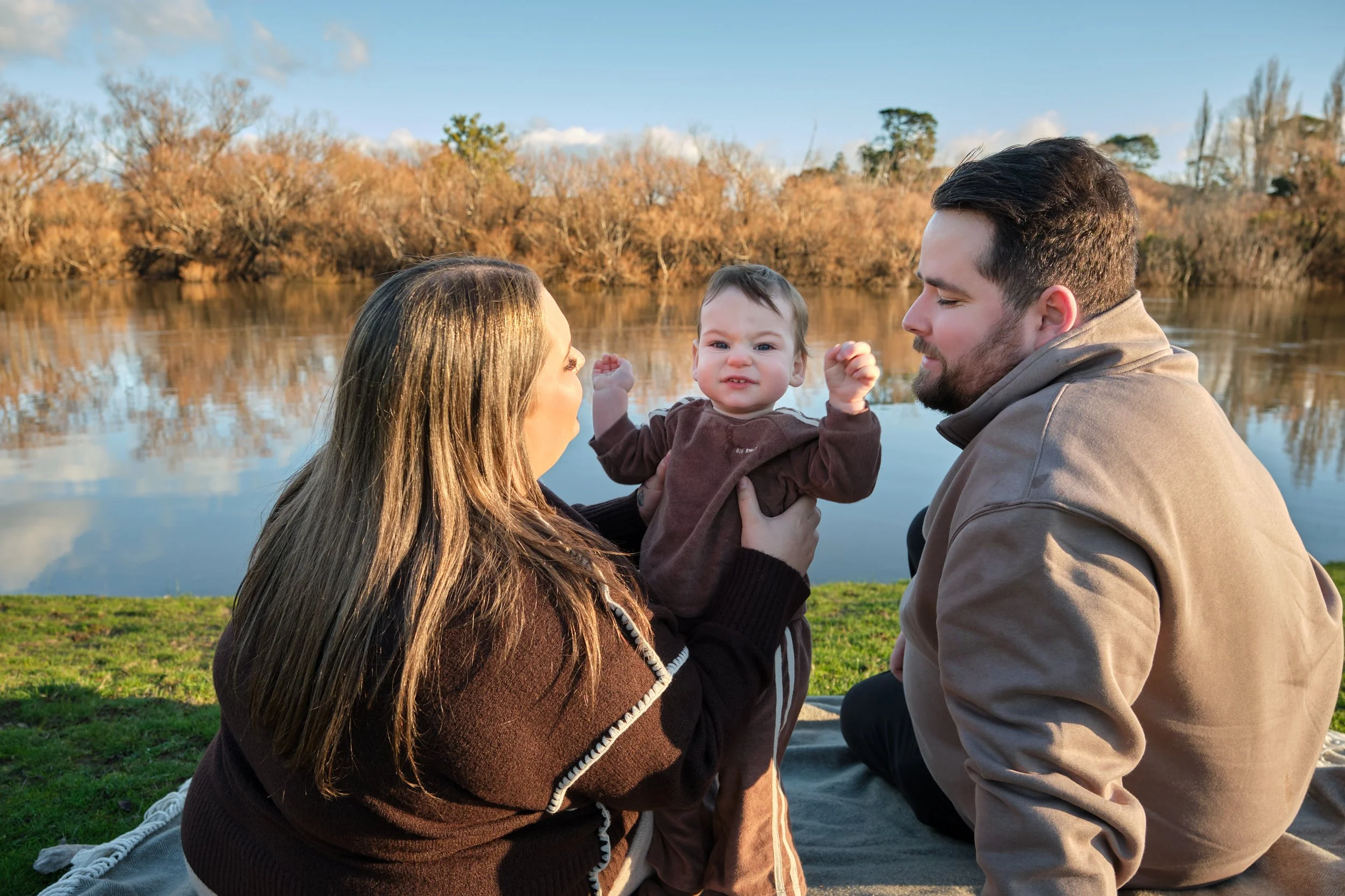 williams-hadspen-river-launceston-family-portrait-session-parents-holding-baby-by-water.jpeg