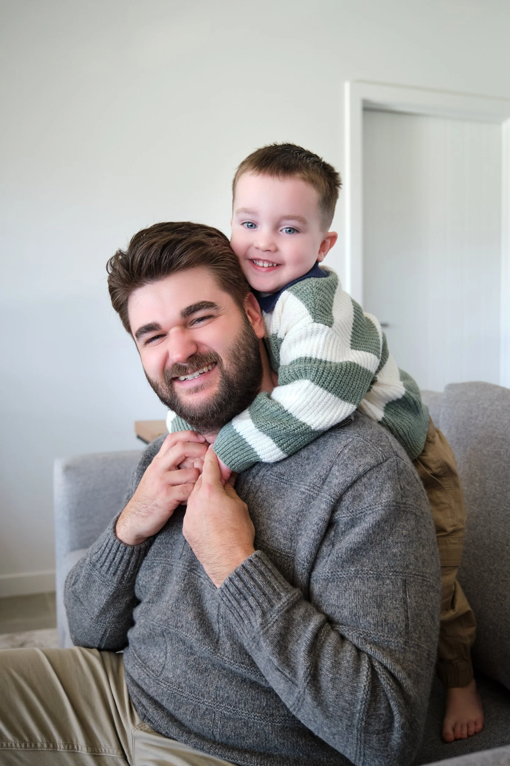 hill-launceston-newborn-family-photography-dad-with-smiling-toddler-hugging-his-neck.jpeg