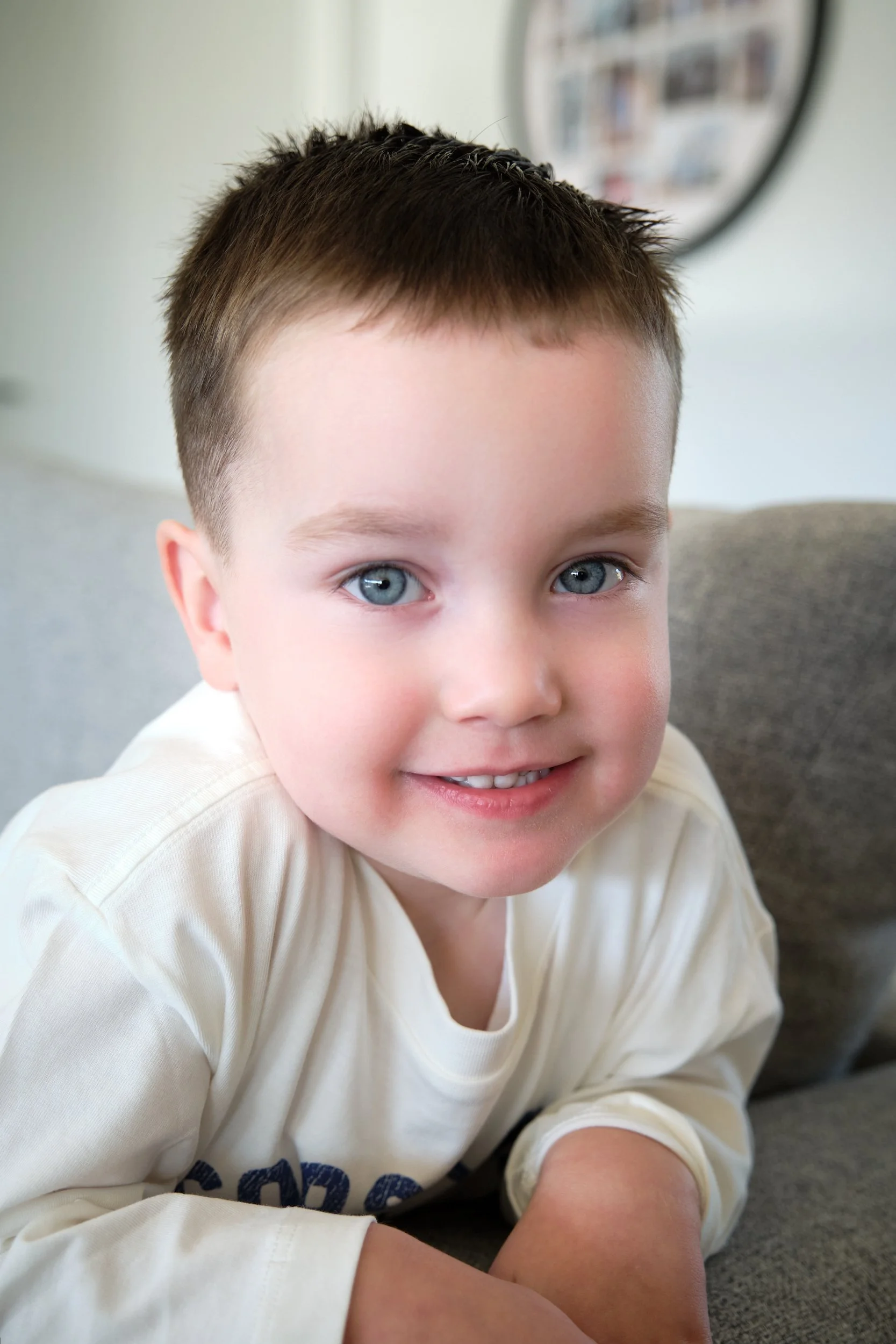 hill-launceston-newborn-family-photography-young-boy-smiling-on-grey-couch.jpeg