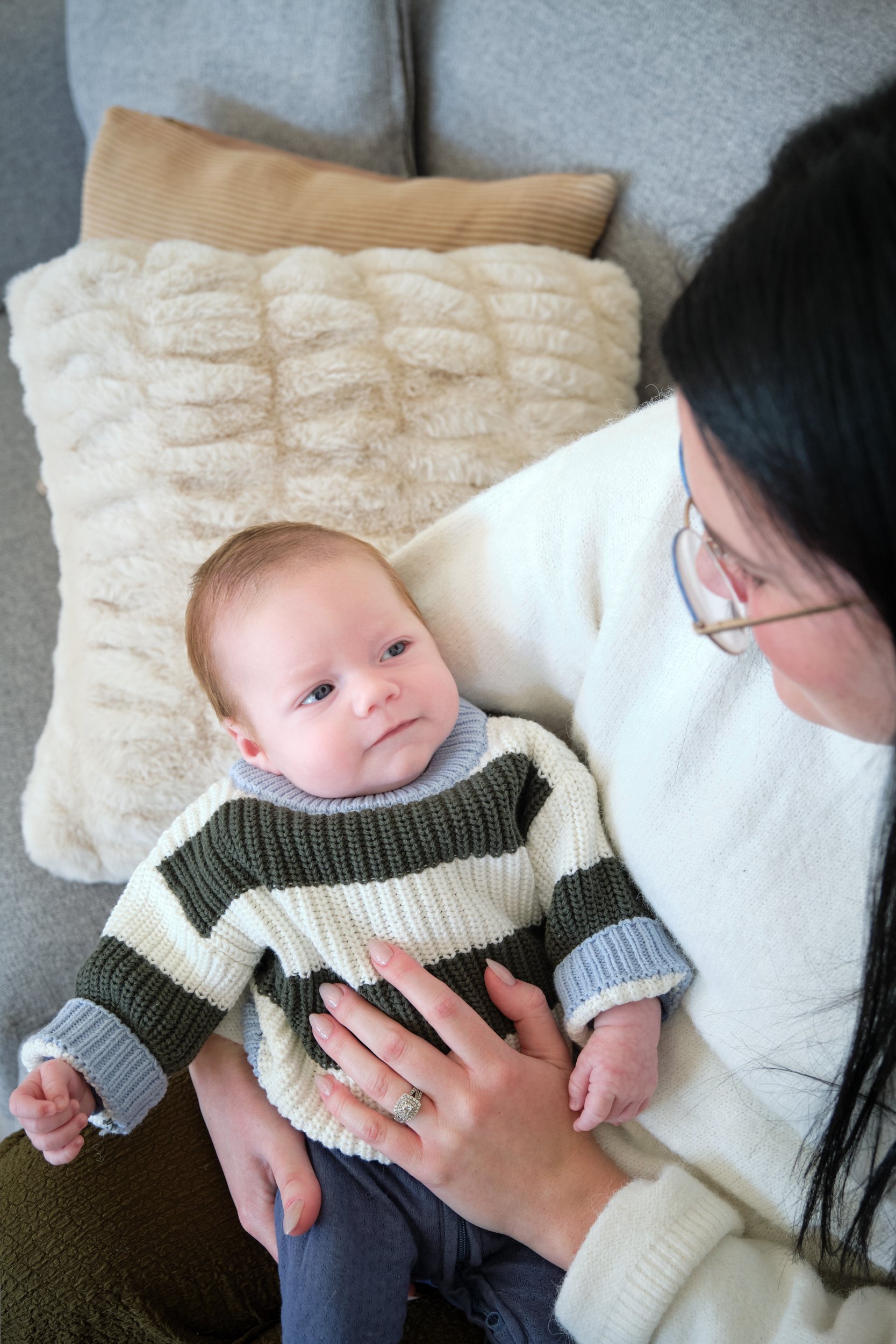 hill-launceston-newborn-family-photography-baby-in-striped-sweater-cuddled-by-mother-on-couch.jpeg