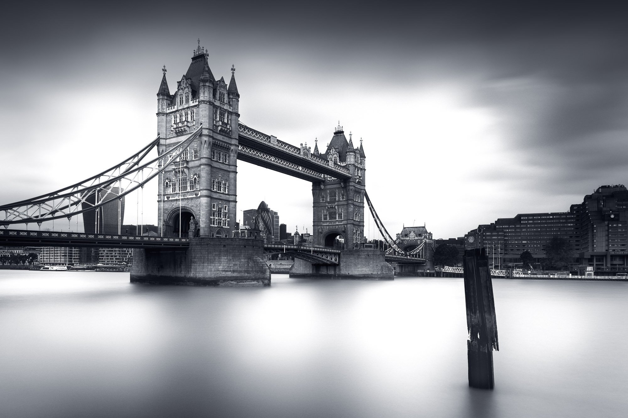 Tower Bridge mirrored in smooth water—moody atmosphere in long exposure black and white.