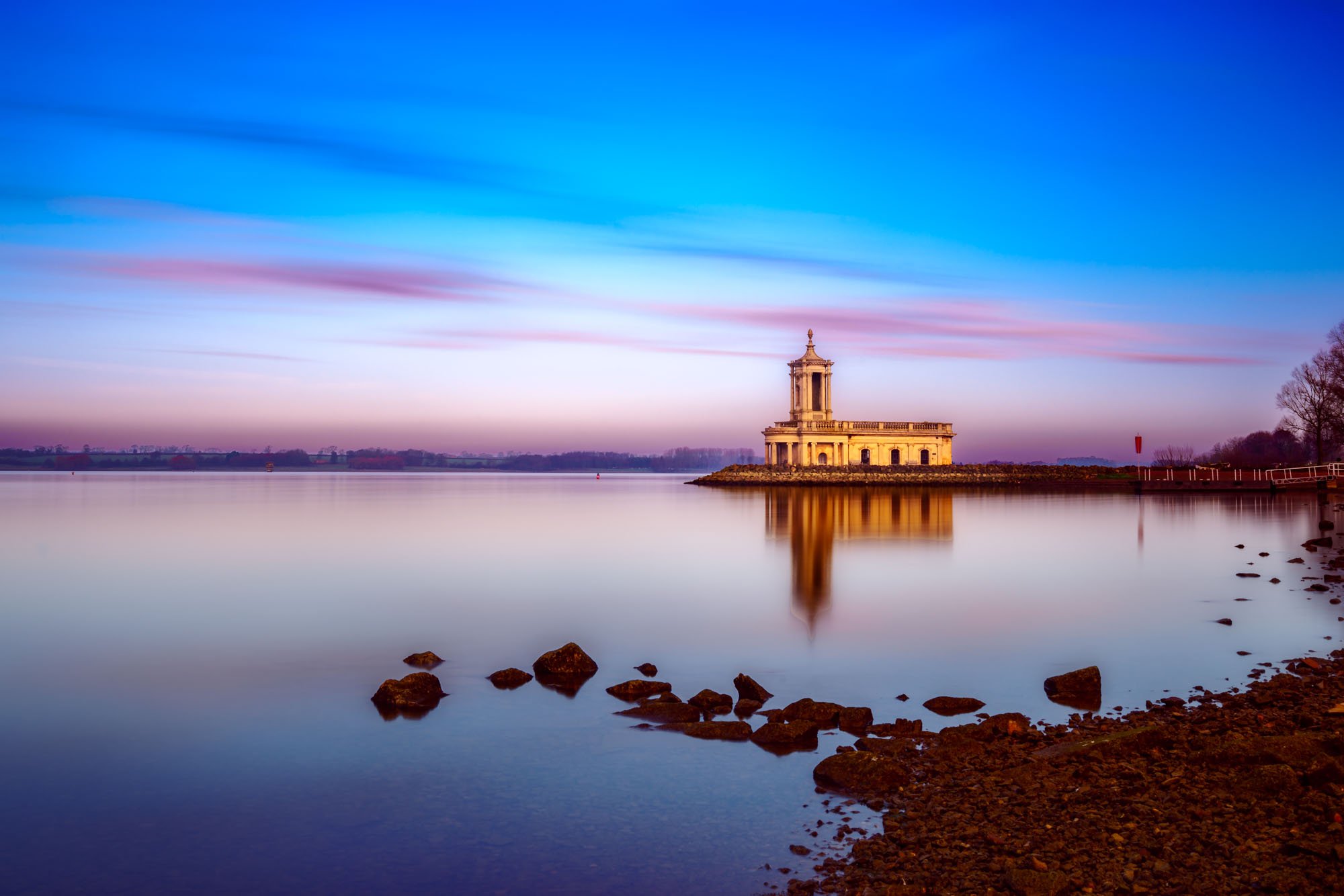 Normanton Church in Rutland Water viewed in the distance with soft blue sky