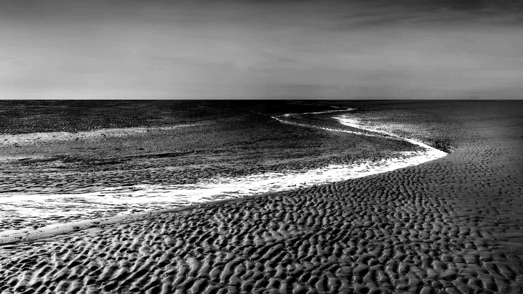 Black and white image of sand patterns and tide lines at Burnham beach
