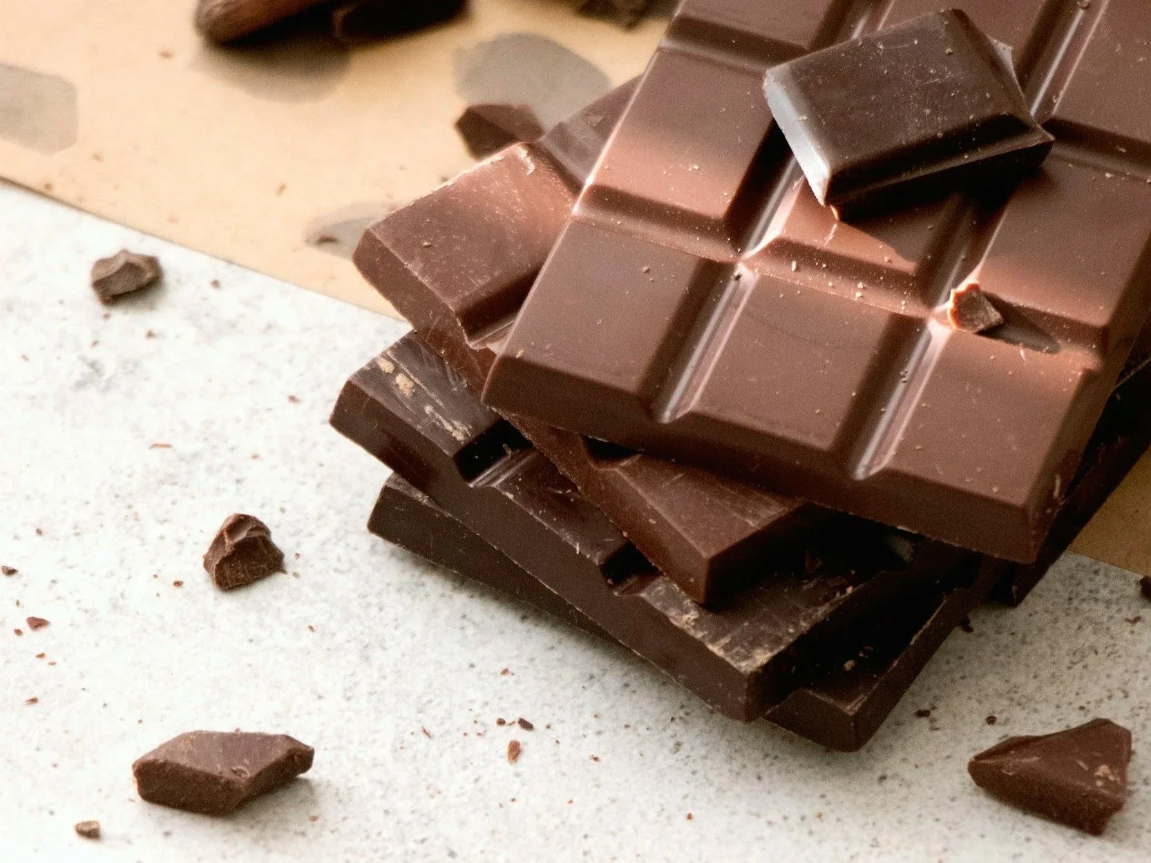 Several bars of chocolate lay crumbling on a grey work surface.