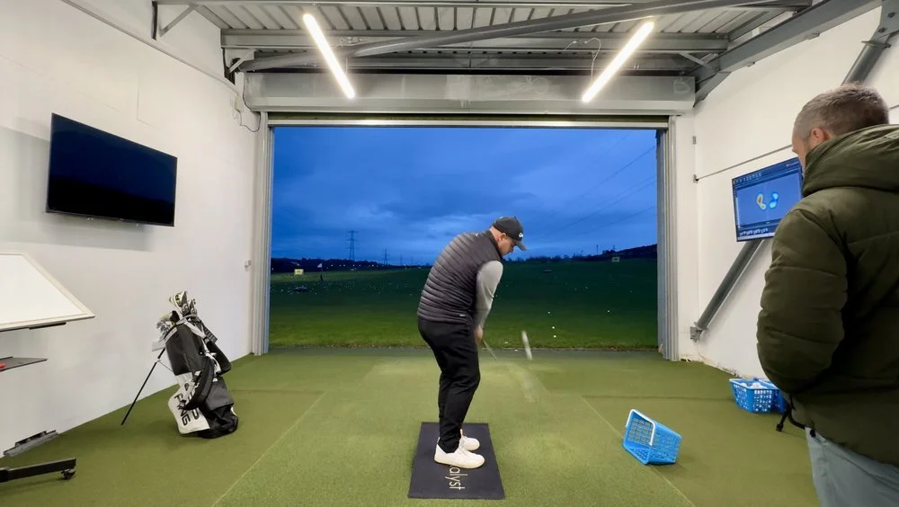 A golfer hitting into the TrackMan screen in the studio at Swanston
