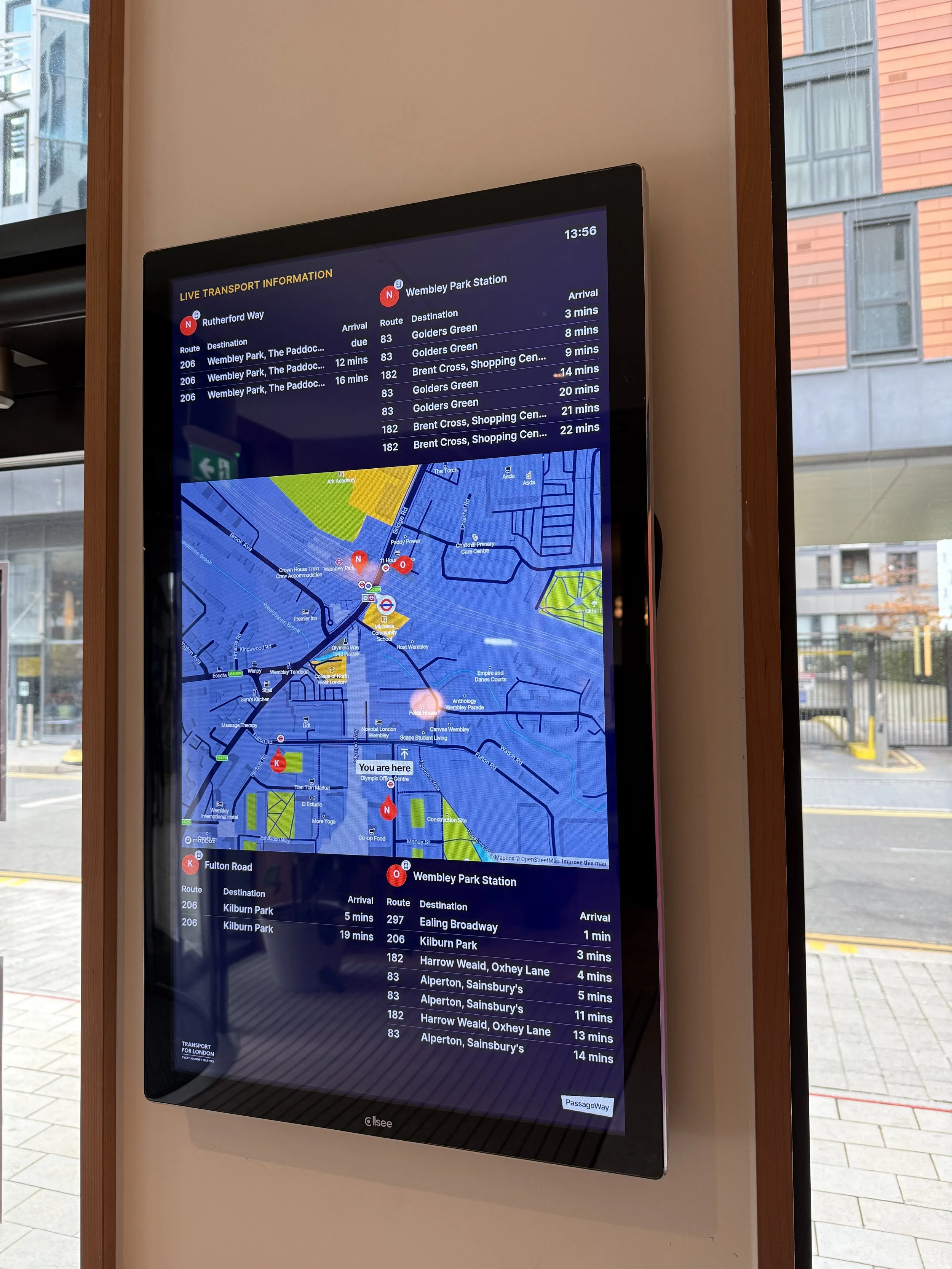 A PassageWay multi modal RTPI digital sign showing live local public transport information on display at a student residence block in London