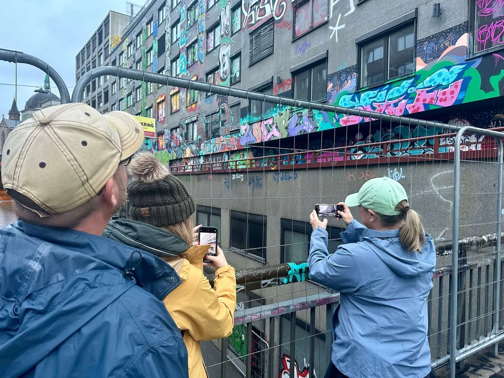  Forbipasserende stopper for å ta bilder av graffitikunsten i Møllergata 37 i Oslo.  Foto: Cathrine Gram 