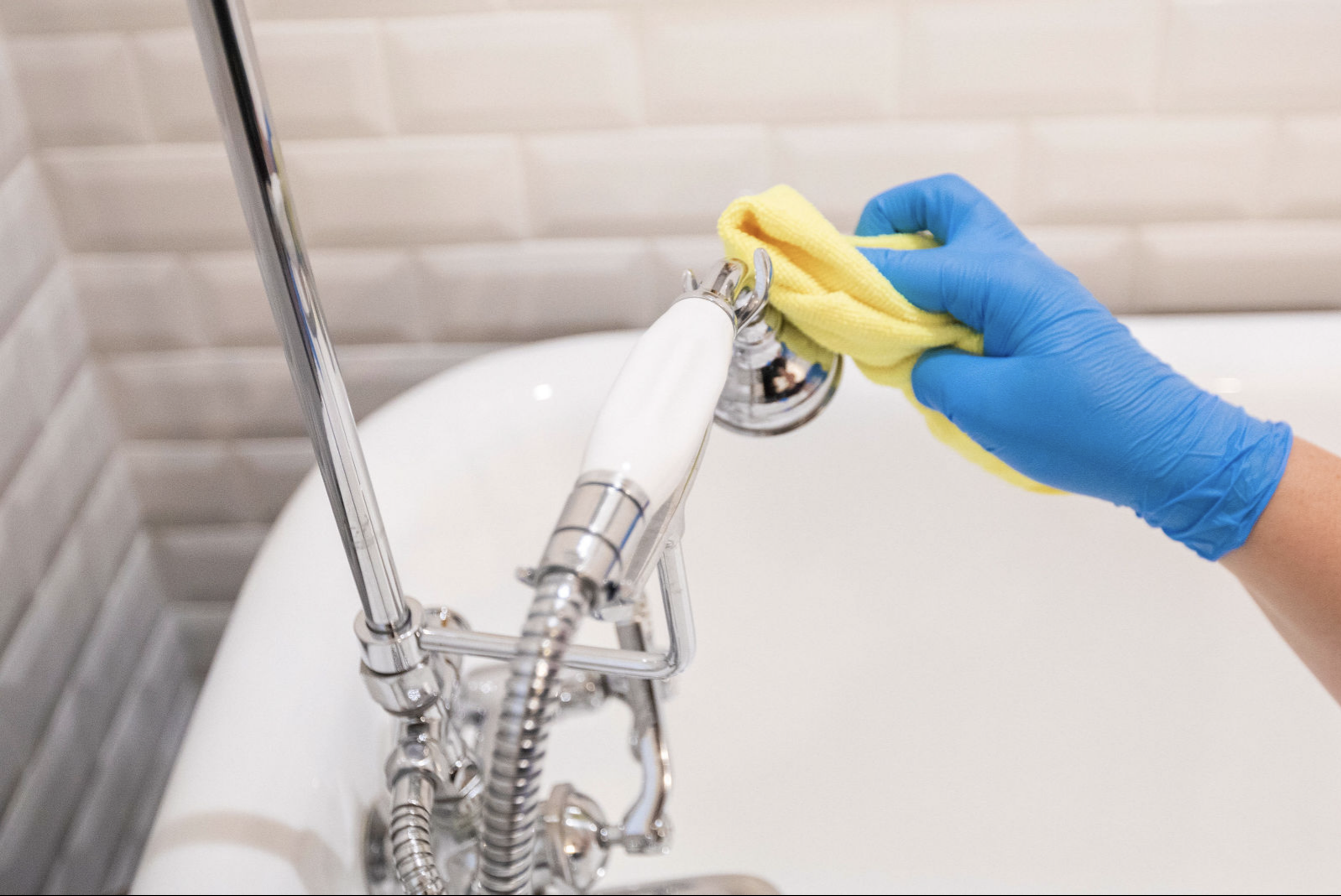 A King’s Green Cleaning professional polishes a bathtub fixture to a brilliant shine, reflecting the company’s dedication to detail and pristine results.