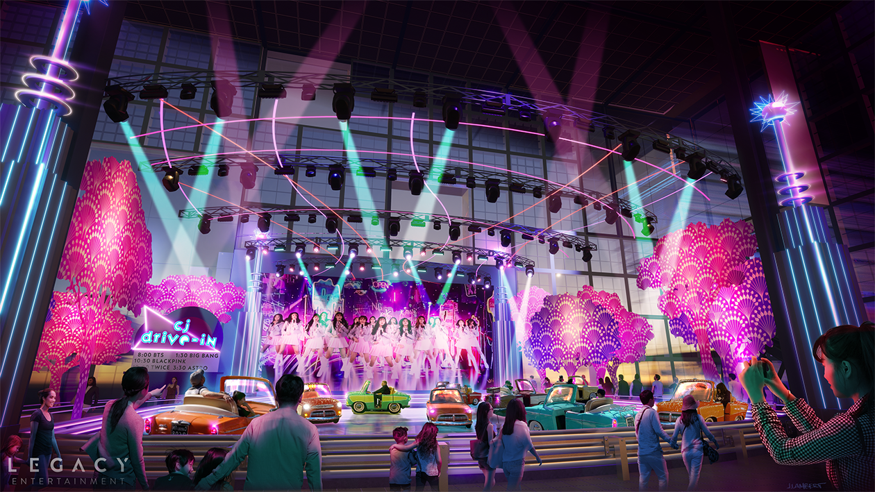 Indoor entertainment venue with a neon-lit stage featuring a large group of K-Pop performers, surrounded by colorful neon trees and a vintage cars ride, with audience members watching and taking photos.