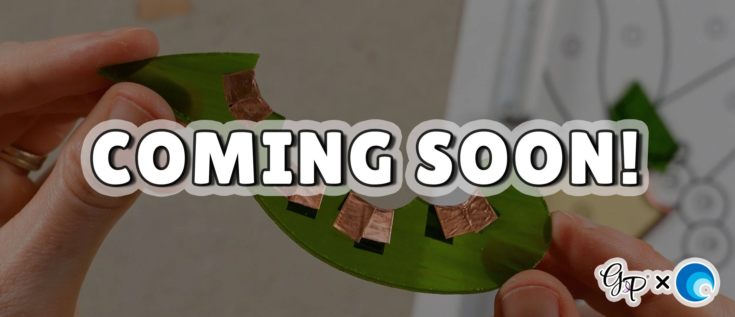 A green leaf-shaped stained glass piece with several copper foil saddles adhered along its concave curves with 'COMING SOON' text overlay