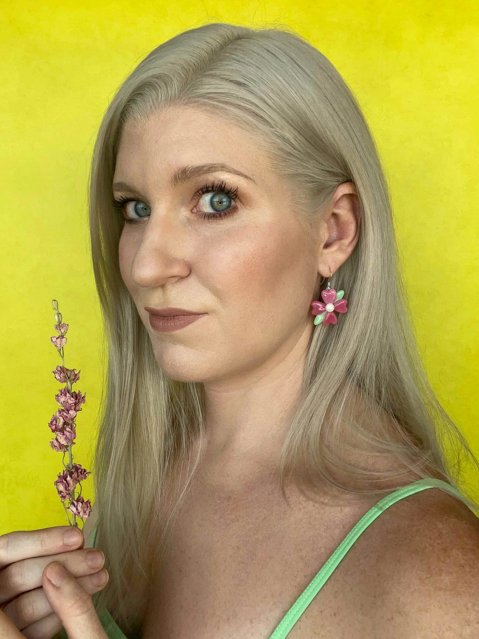 Jackie Knowles wearing fused glass flower earrings and holding a matching pink flower