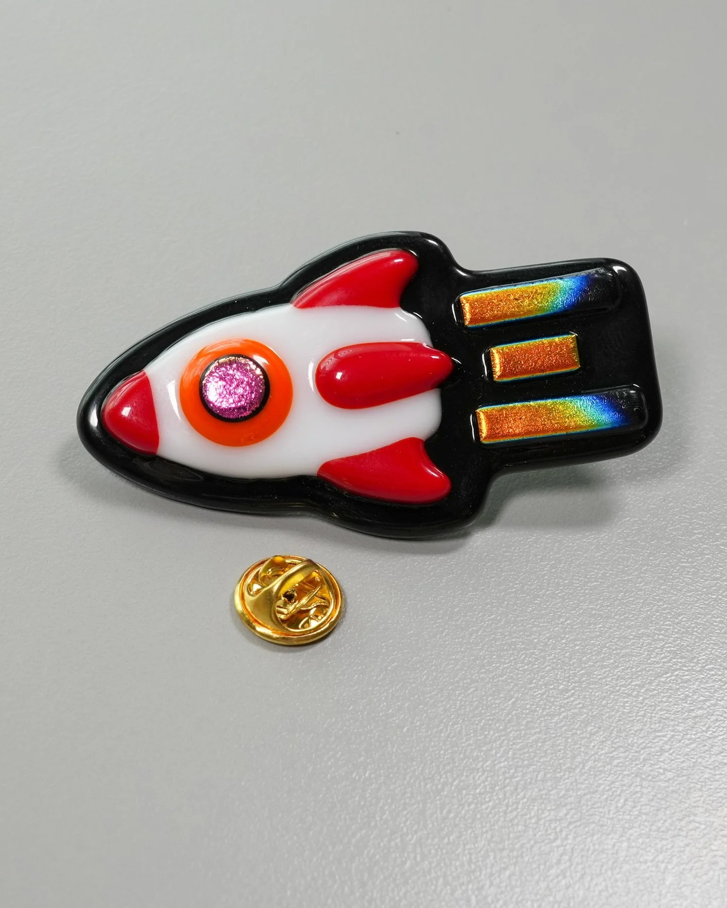 Running on Rainbows 🚀

I created this spacey pin during production of the Bonus Lesson of my Fusing Fundamentals series to show how I was personally inspired by a unique trait of dichroic glass. I noticed that the rainbow coating on some dichroic no