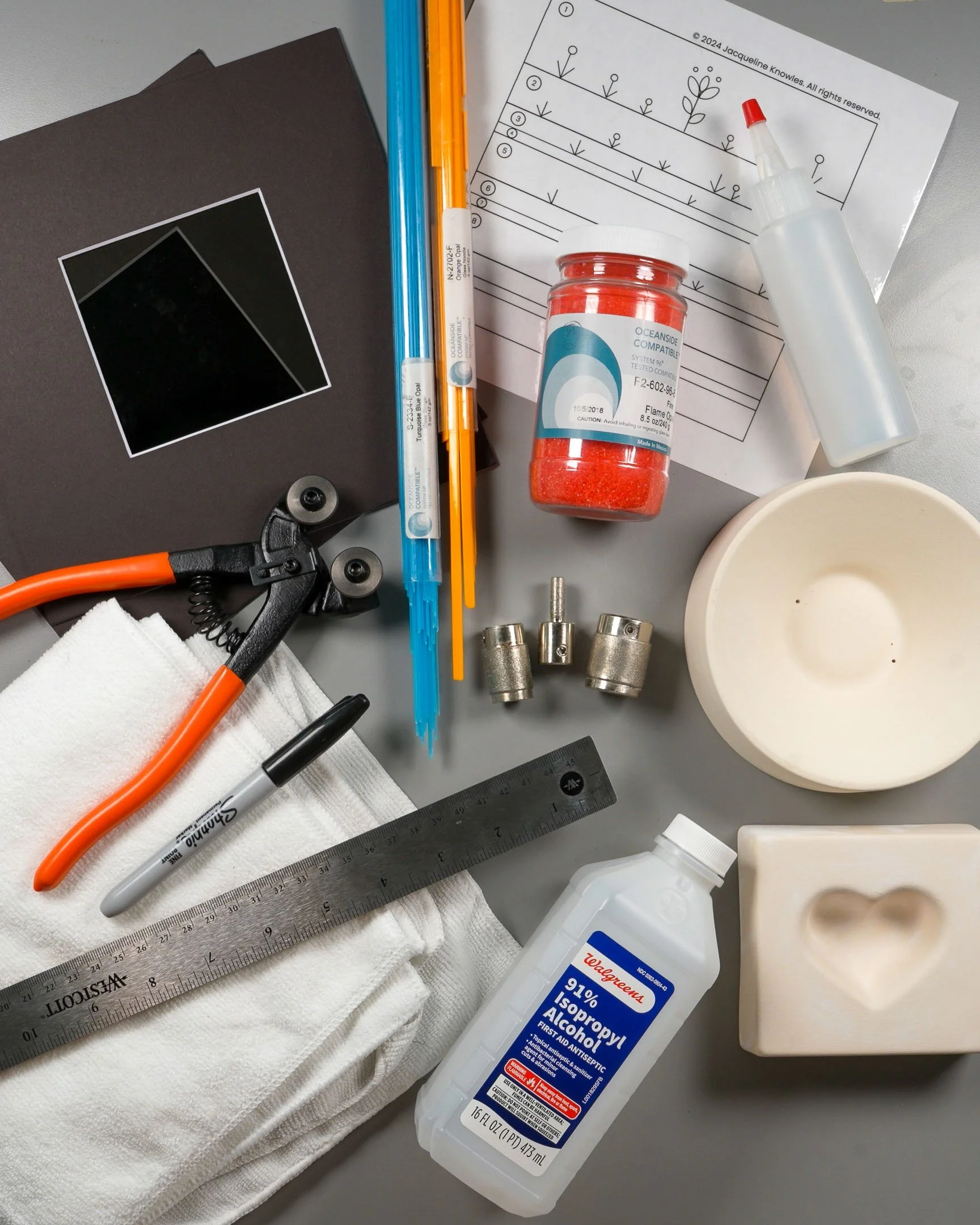Various glass fusing tools and materials spread on a work surface