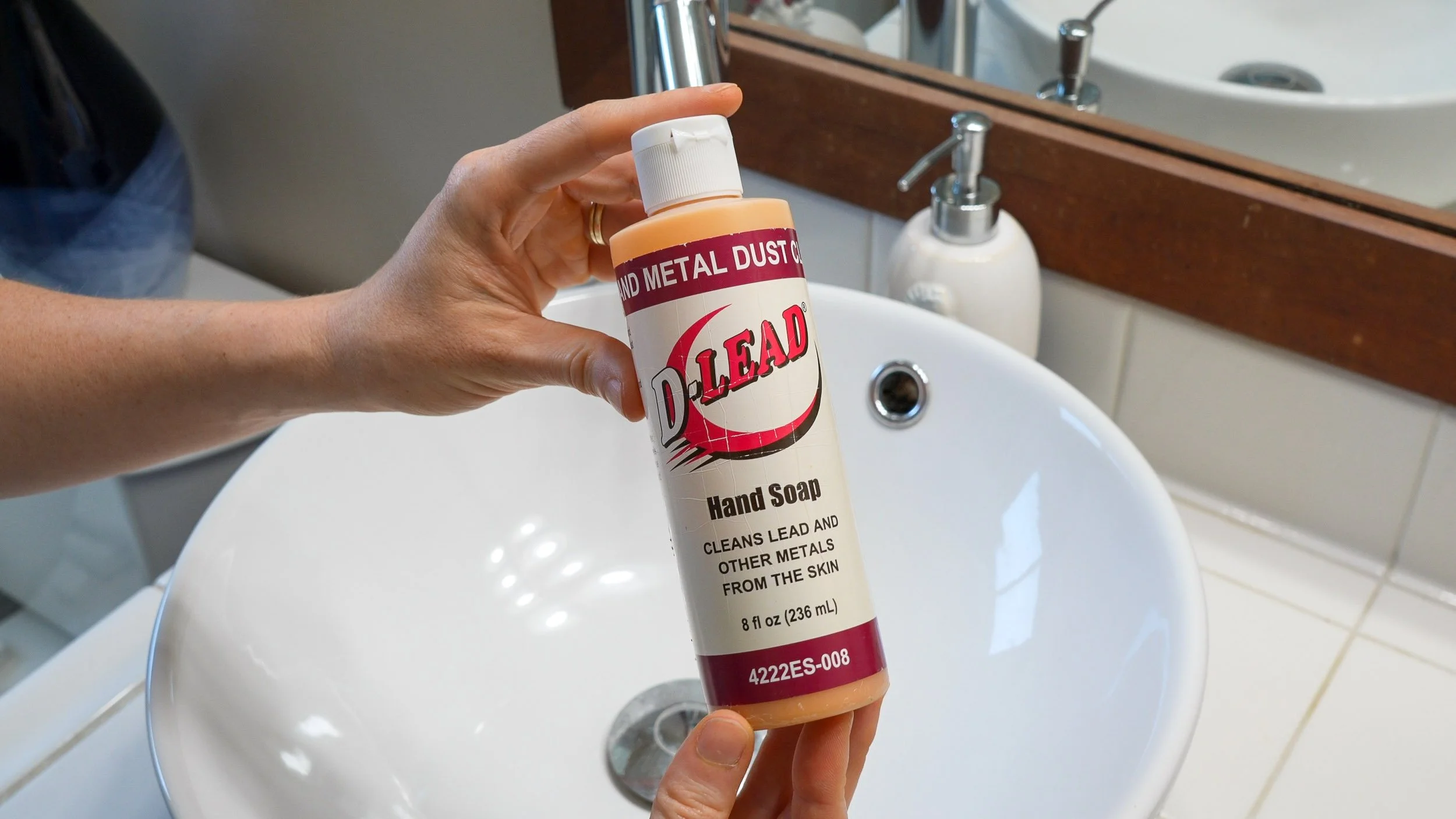 Hands holding de-leading soap above a bathroom sink