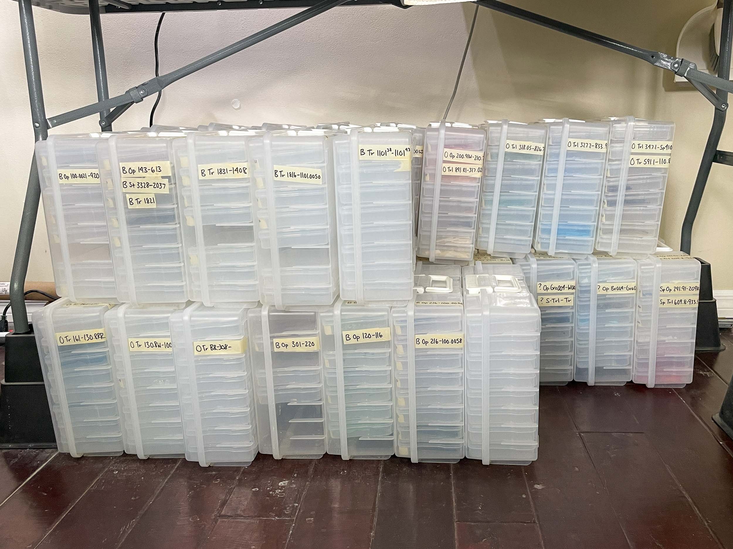 Several photo storage containers holding stained glass scraps, arranged in ordered stacks
