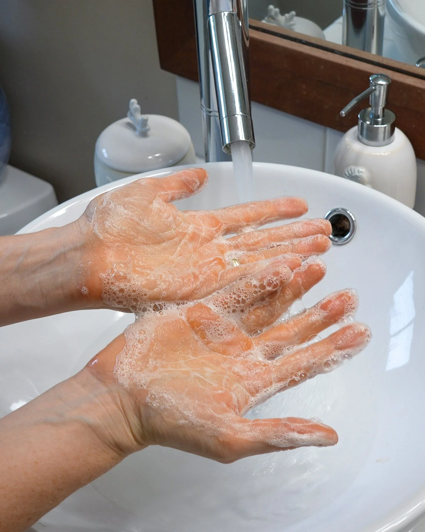 Hands lathering with de-leading hand soap in a bathroom sink