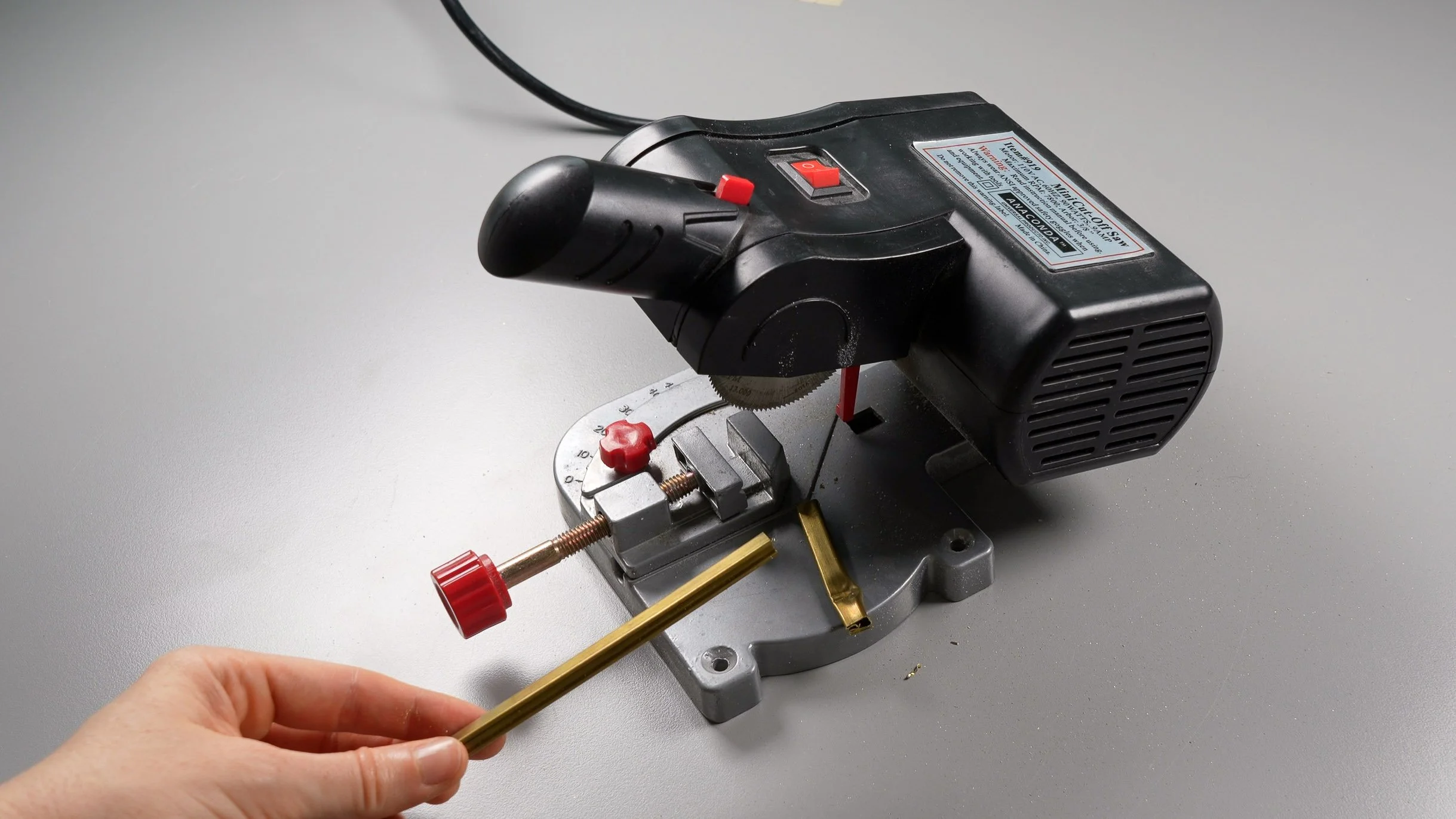 A mini miter saw cutting a segment of brass came framing channel