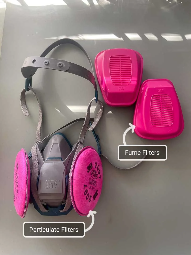 A 3M respirator with particulate filters next to a pair of fume filters