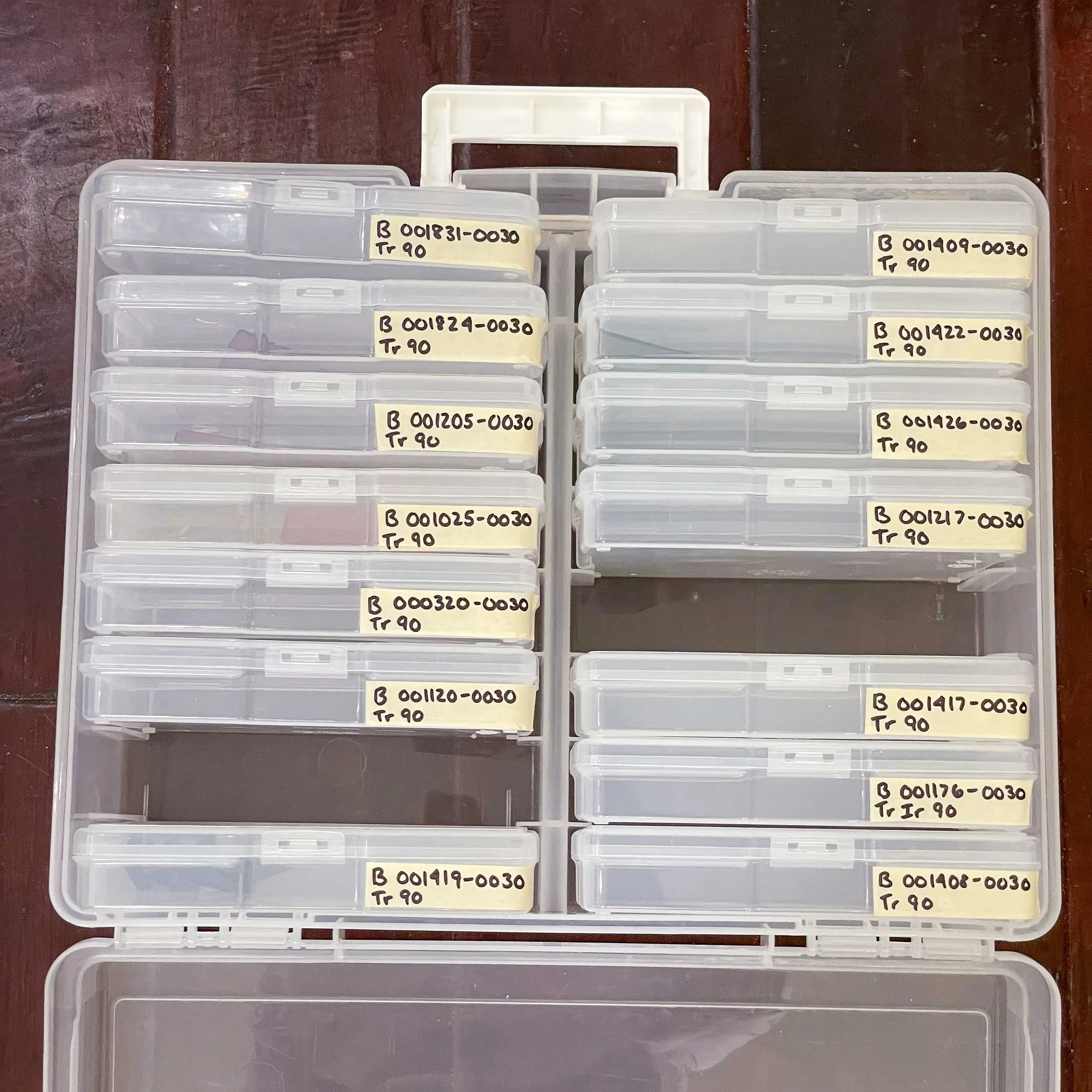 An open photo storage container with several smaller photo containers nested inside, each labeled with a type of stained glass
