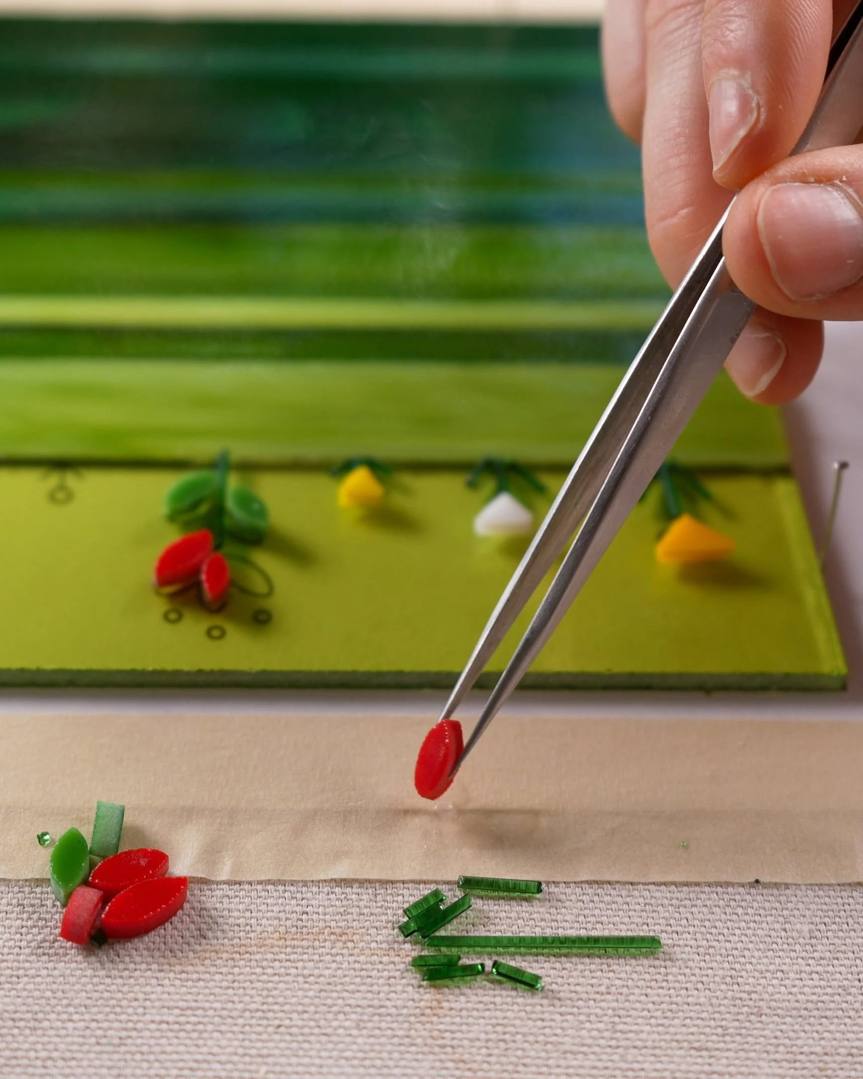 Flower-shaped glass pieces being added to a fused glass project