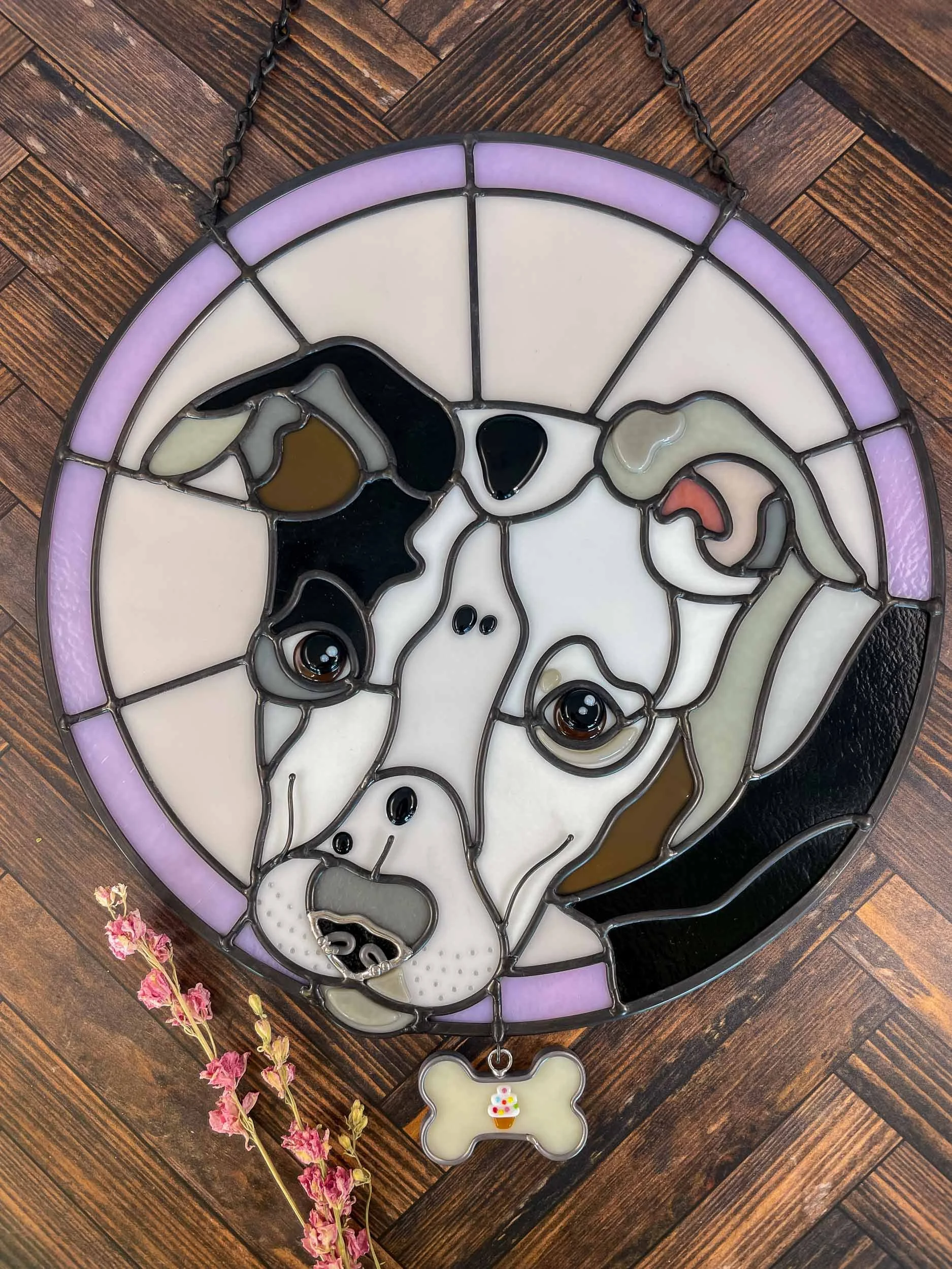 A stained glass pet portrait of a dog surrounded by a pink background