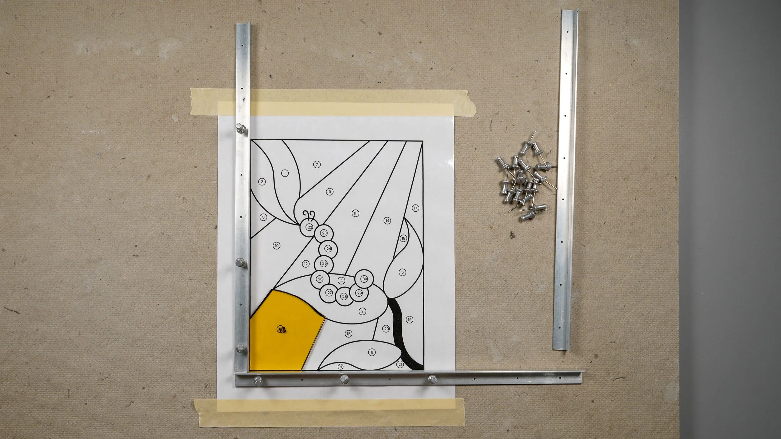 A partially-constructed stained glass project with layout blocks tacked around it