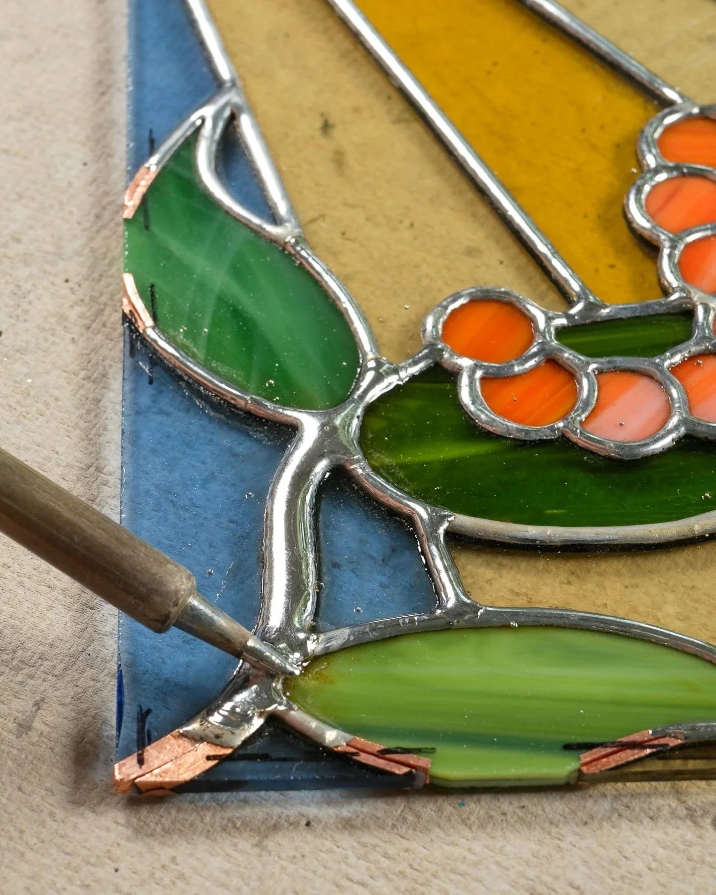 A soldering iron soldering the copper foil seam of a stained glass project