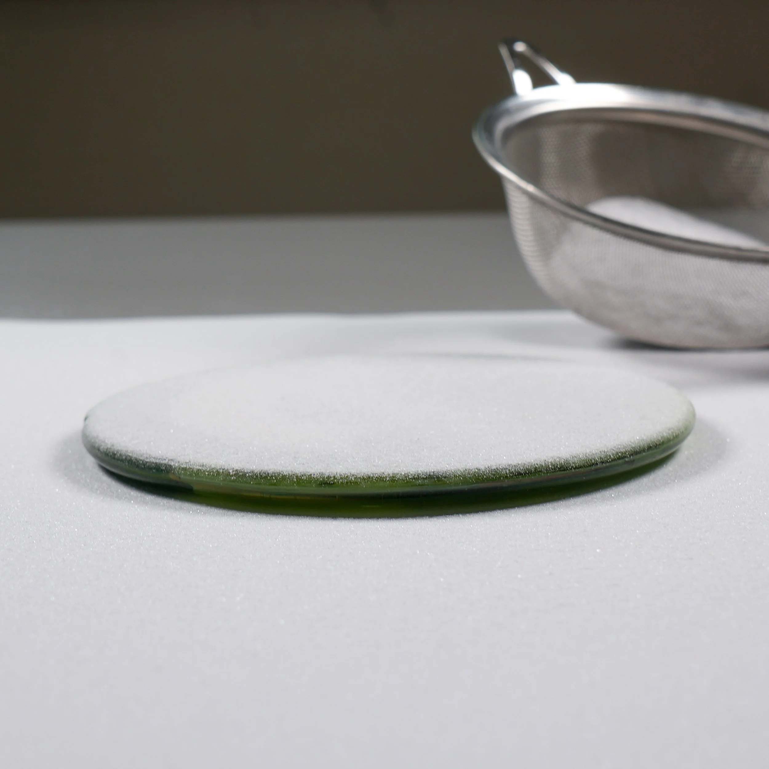 A layer of clear powder frit sifted over top of a fused glass project with devitrification