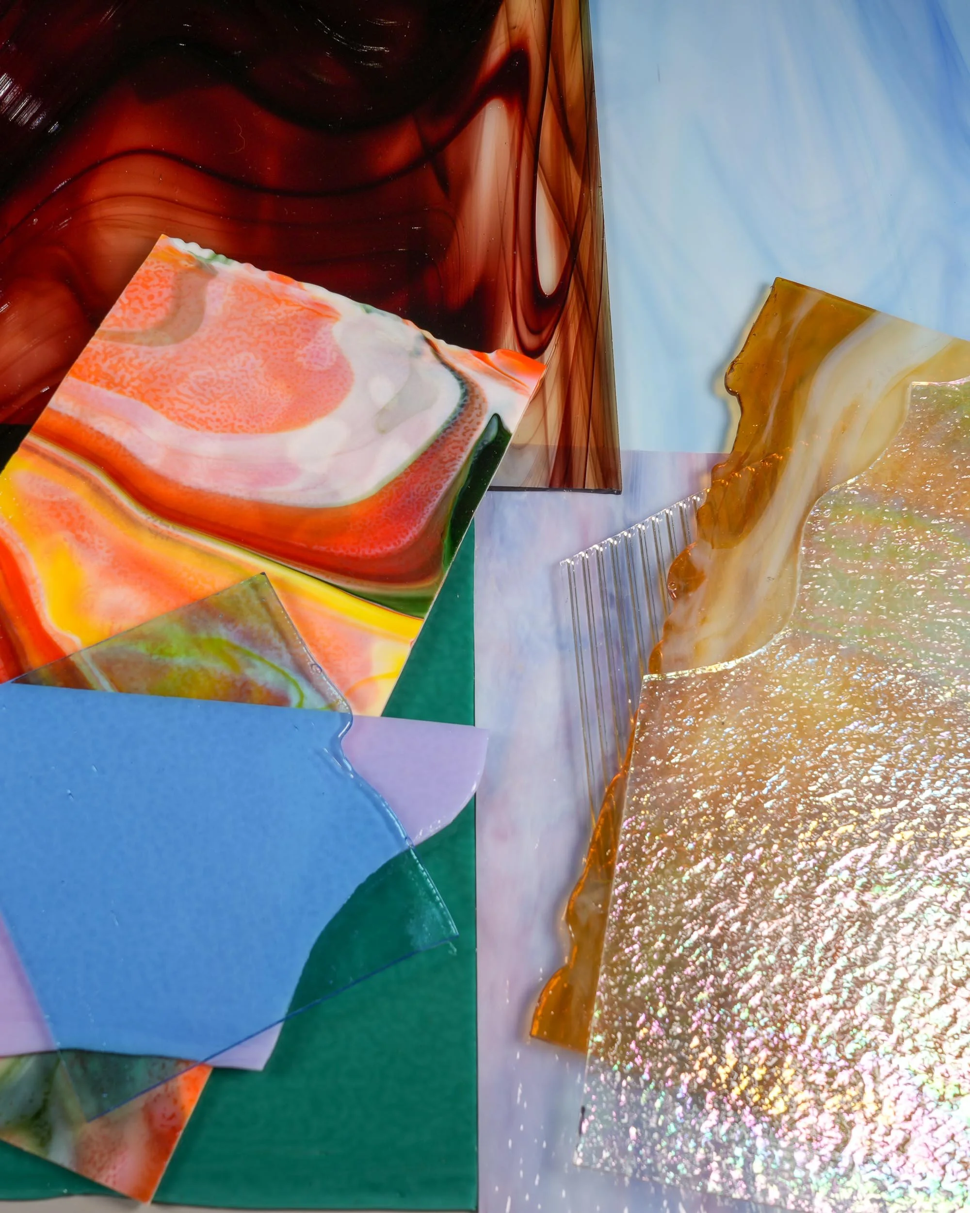 Numerous stained glass sheets of various colors, textures, and sizes