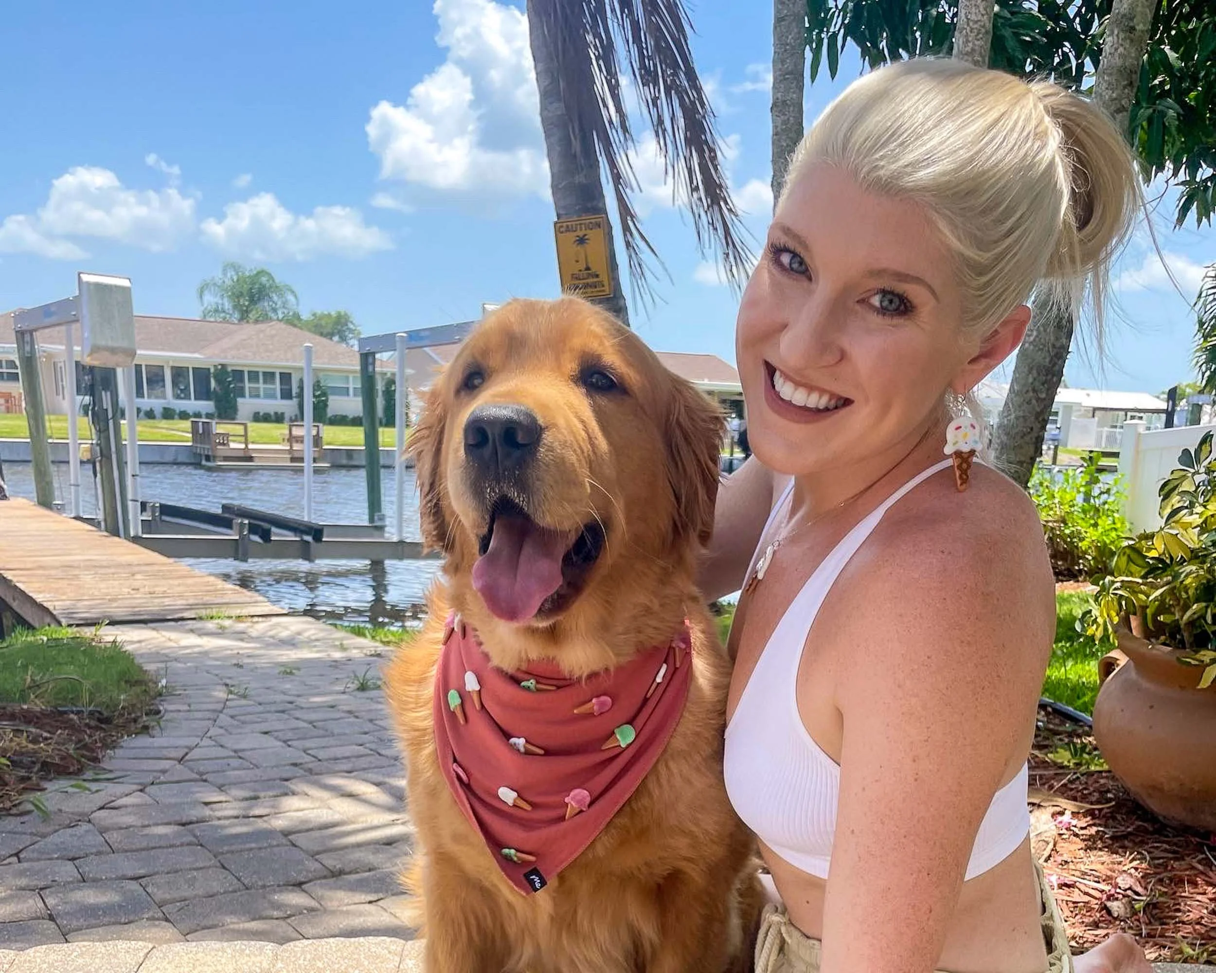 Jackie Knowles with her arm around a Golden Retriever, sitting in front of a sunny waterview