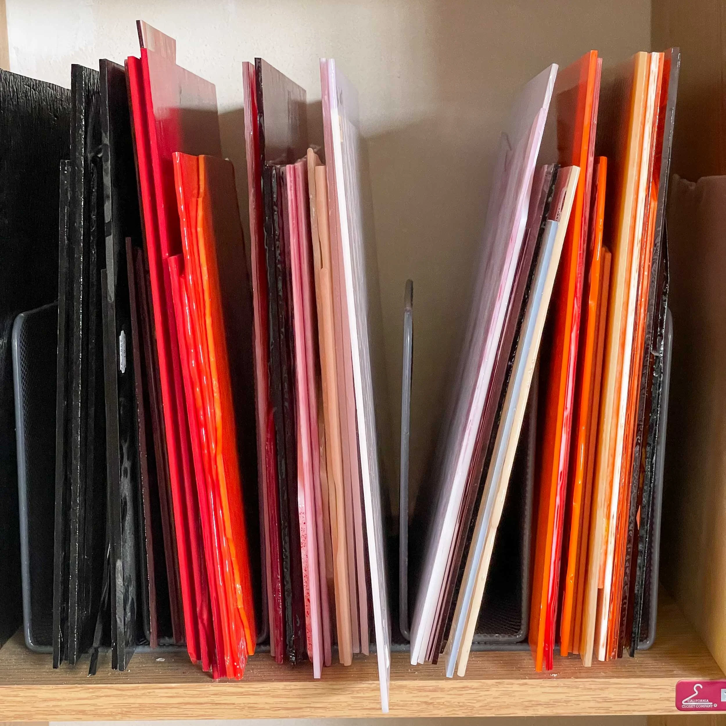 Various medium-sized stained glass sheets stored in a metal file organizer